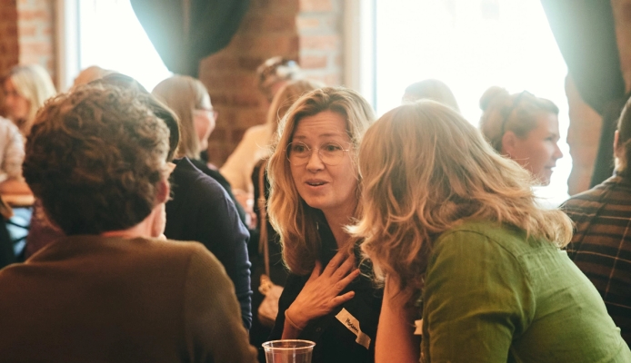 a group of women are sitting at a table talking to each other .