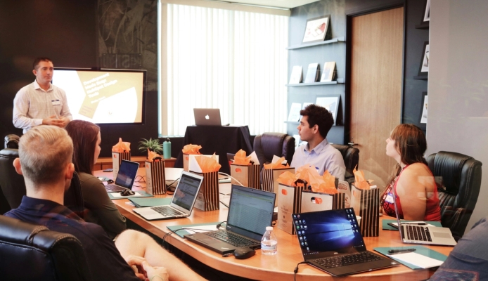 a group of people are sitting around a table with laptops in a conference room .