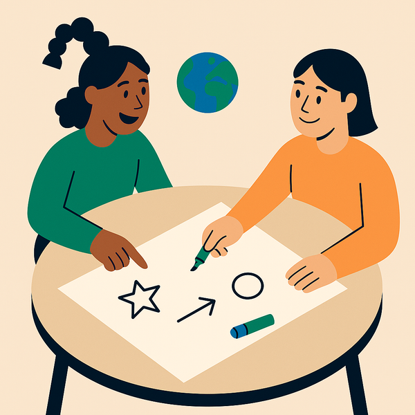 To jenter sitter ved et bord og tegner på et ark.