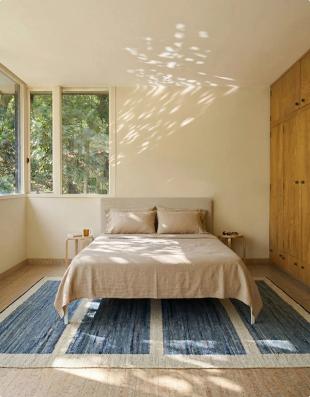 Sunlit bedroom with a blue washable rug under the bed