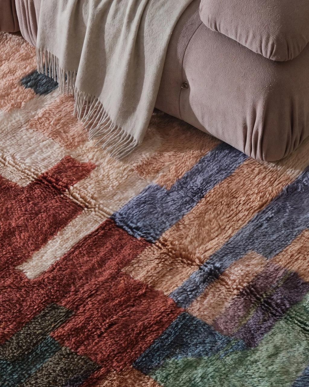 Stack of solid-color rugs in tan, olive green, blue, burgundy, and dark brown