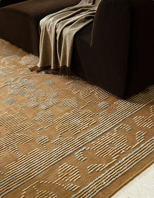 Helen washable rug in brown beneath a dark sofa with a throw blanket