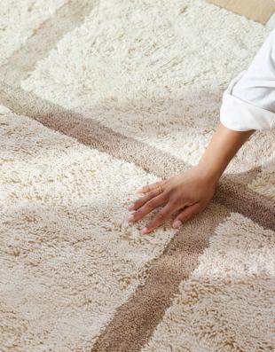 Hand touching the plush surface of the Topstitch washable rug