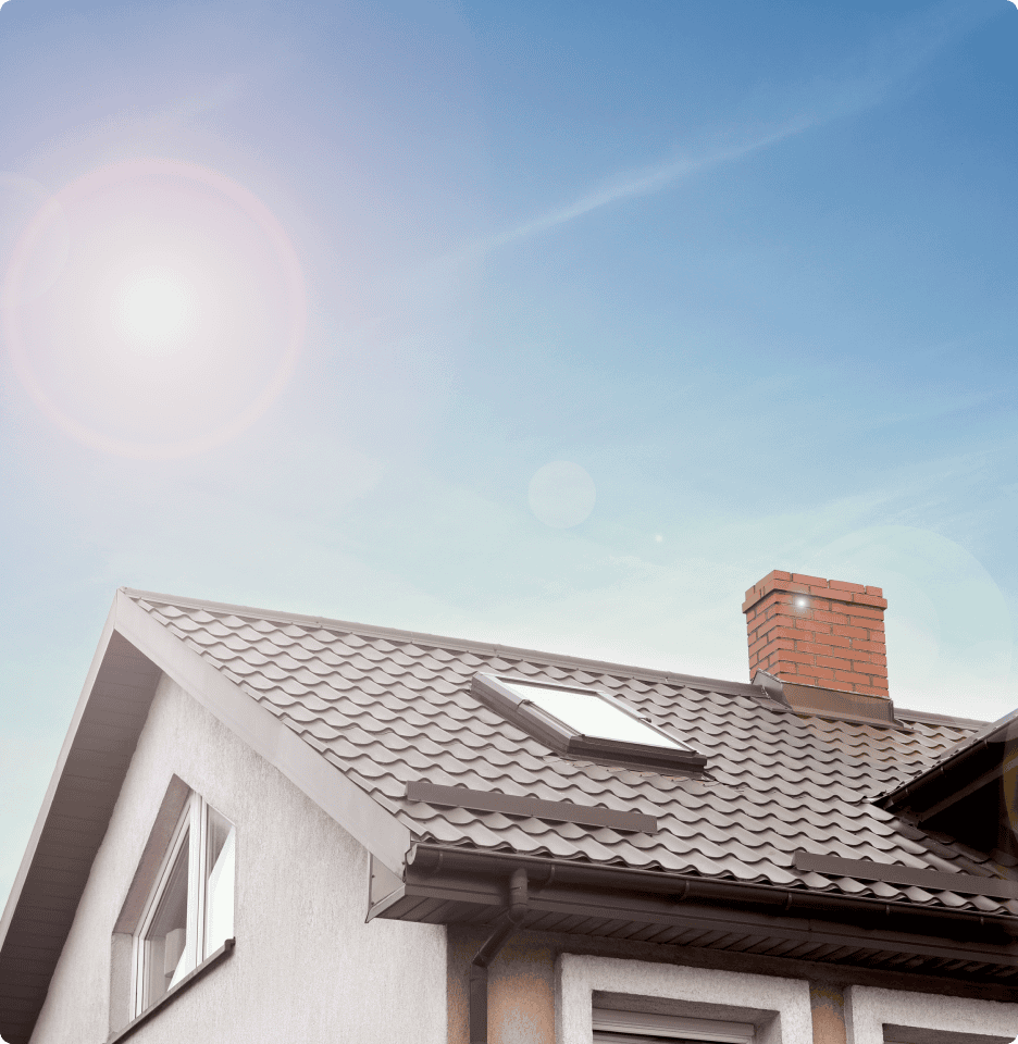 A residential home's tiled roof with a brick chimney and skylight against a bright blue sky.