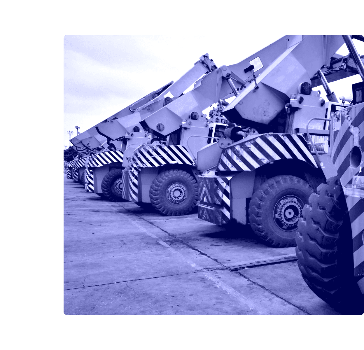 A row of heavy commercial construction machines parked outdoors.