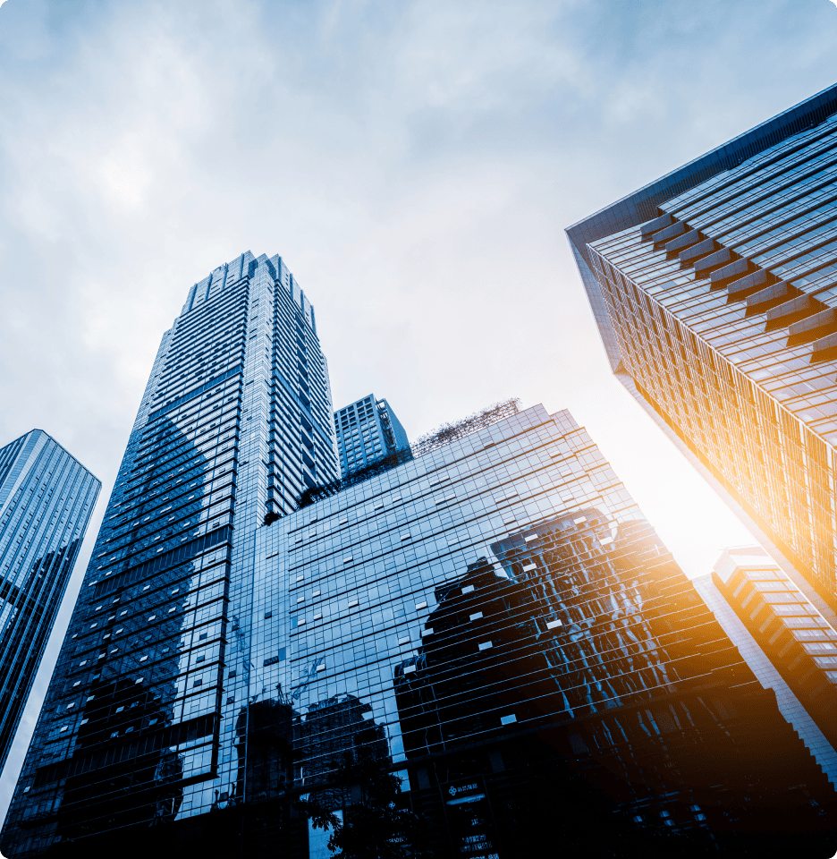 Upward view of glass commercial high-rise office towers against a bright sky.