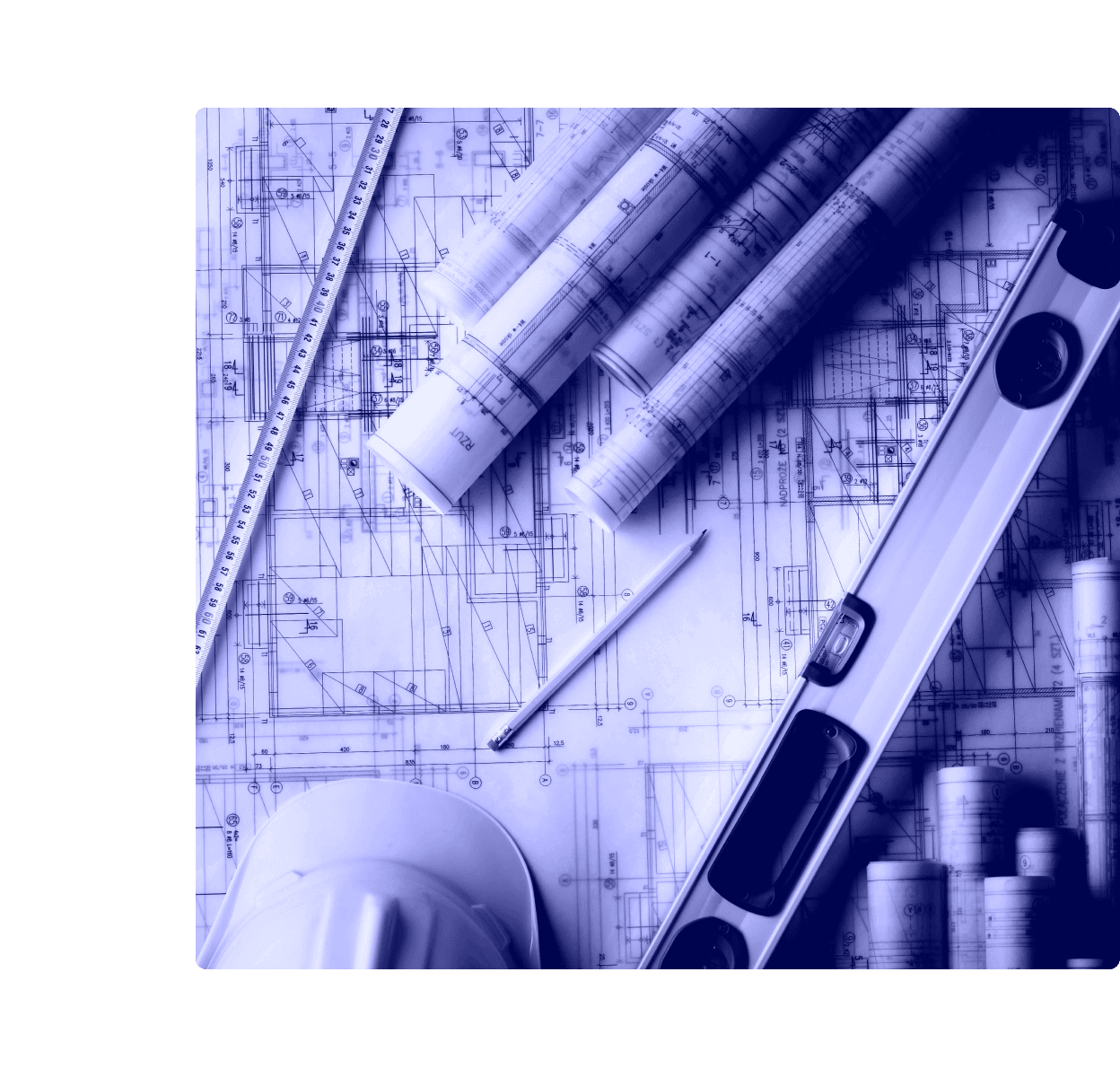 Rolled and flat construction blueprints on a desk alongside a spirit level, pencil, folding ruler, and a white hard hat.