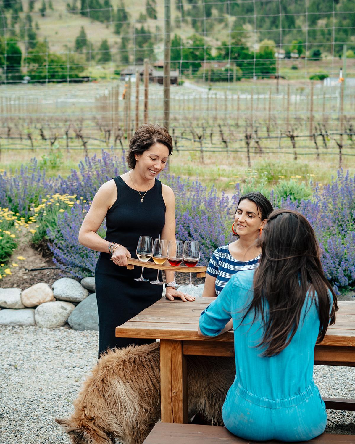 A Roche Wines host pours a tasting flight at an outdoor patio table overlooking the vineyard