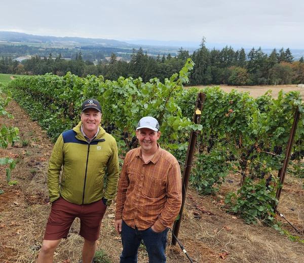 Dylan Roche and Russell Gladhart standing between rows of vines at Winter's Hill in the Dundee Hills, Oregon