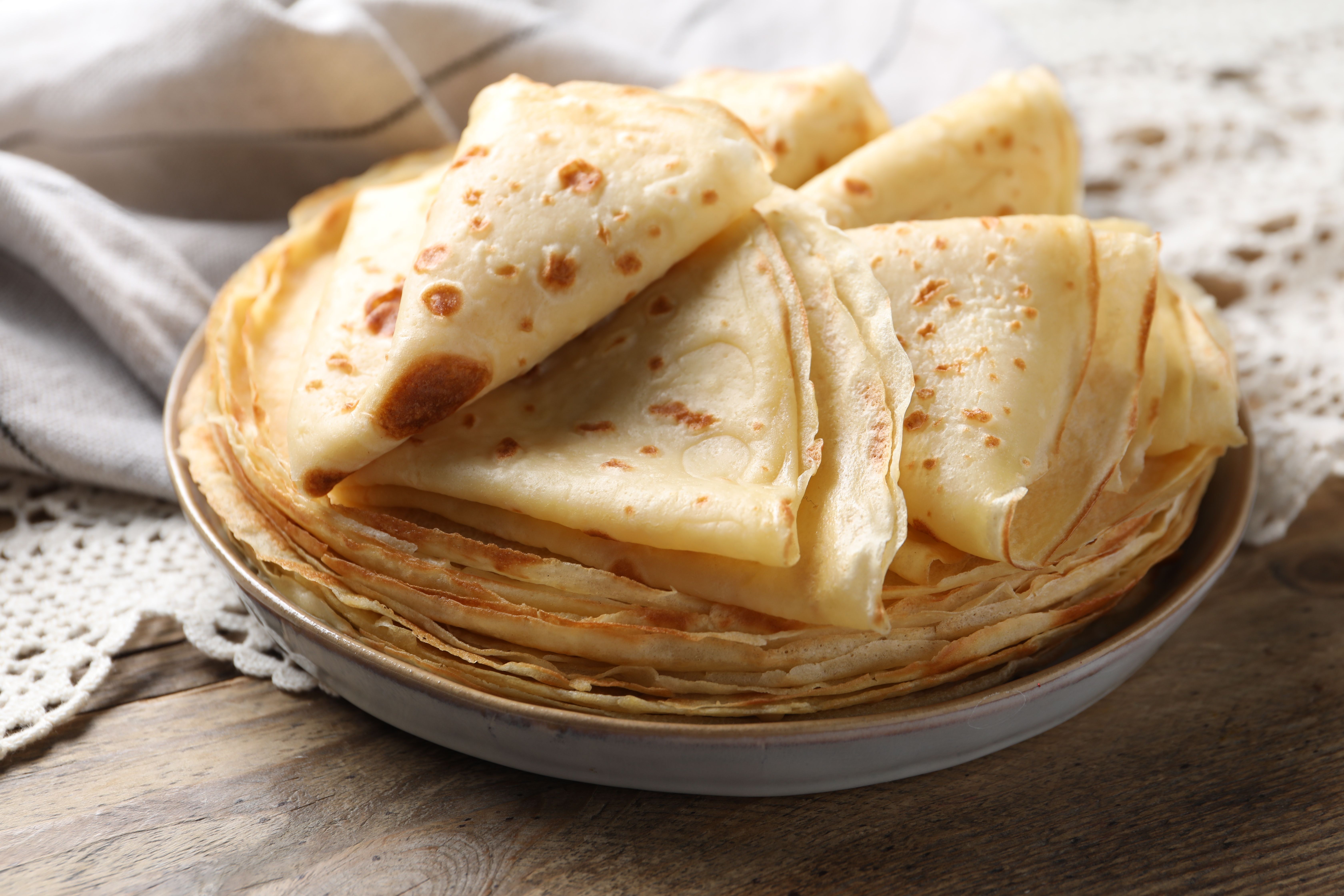 Thin golden crêpes stacked on a plate