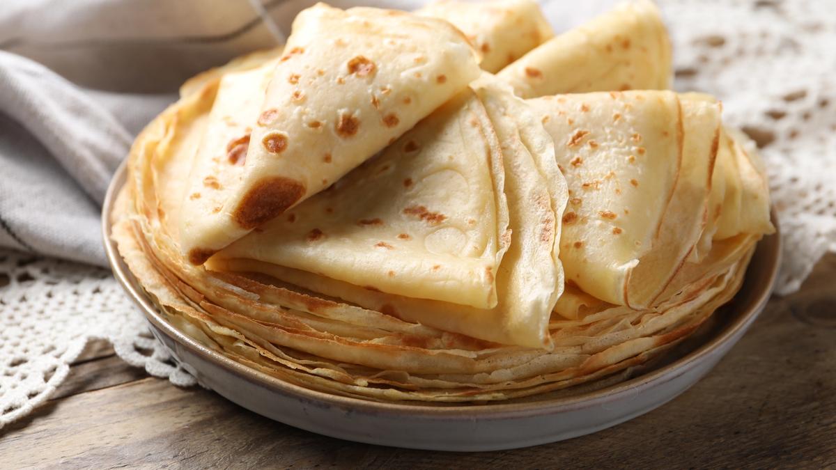 Thin golden crêpes stacked on a plate