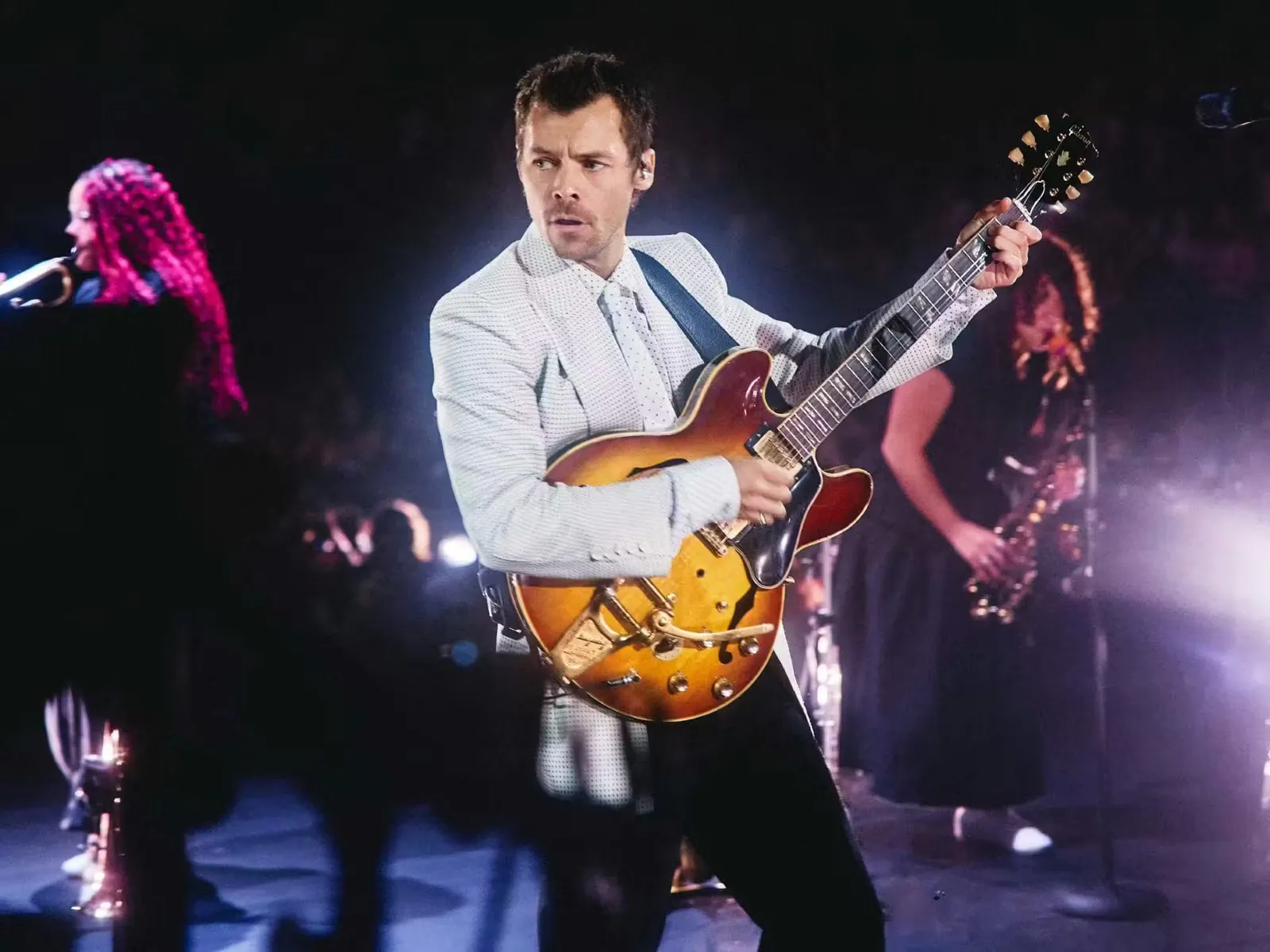 Harry Styles bermain gitar di atas pentas konsert