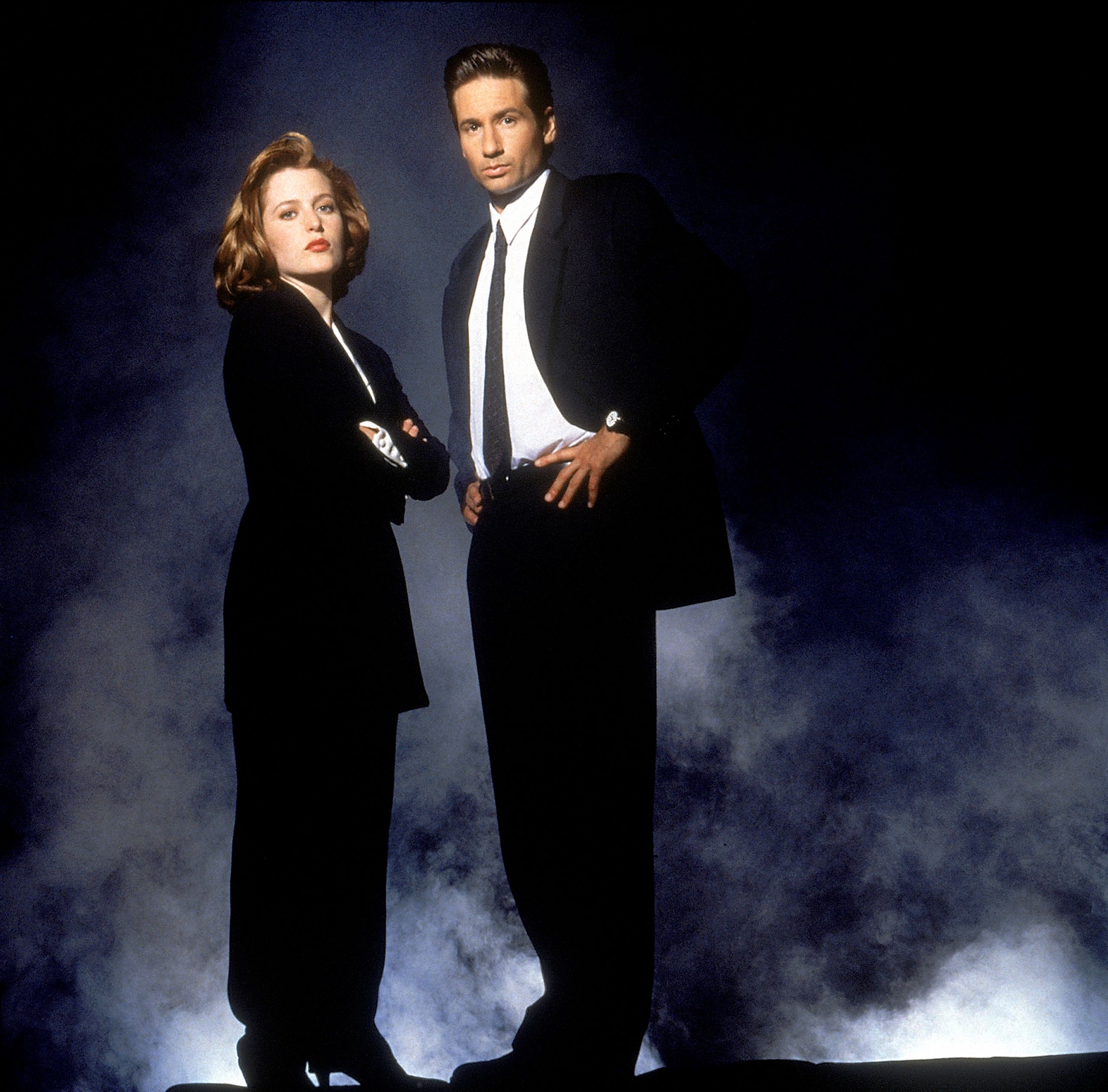 Gambar promosi siri The X-Files: dua ejen FBI bersut hitam berdiri dalam kepulan asap