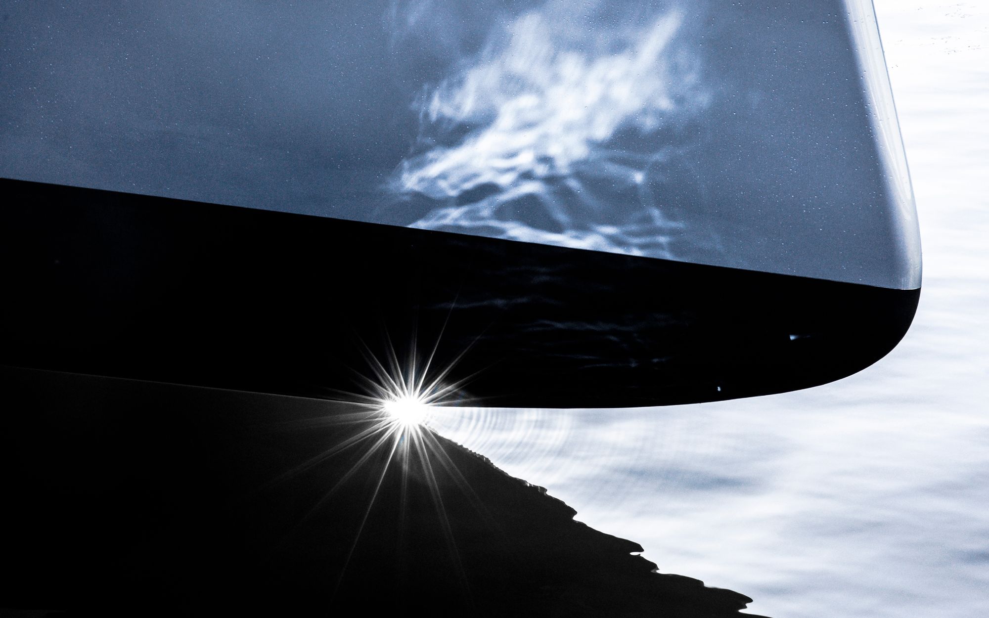 Light reflects on water, revealing the yacht's pure lines in an elegant chiaroscuro