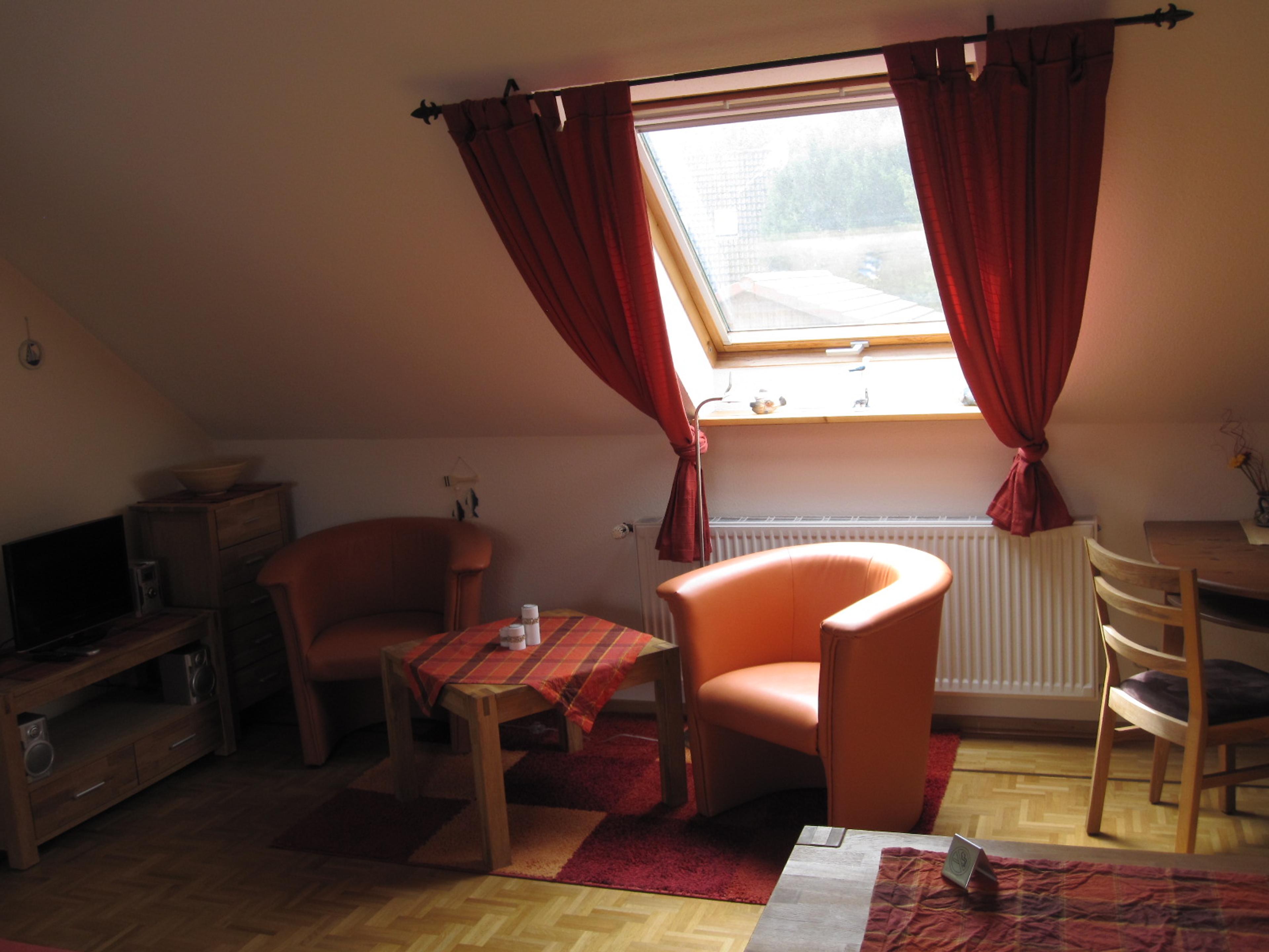 Wohnbereich im Dachgeschoss mit einer Sesselecke und einem Esstisch und Stühlen