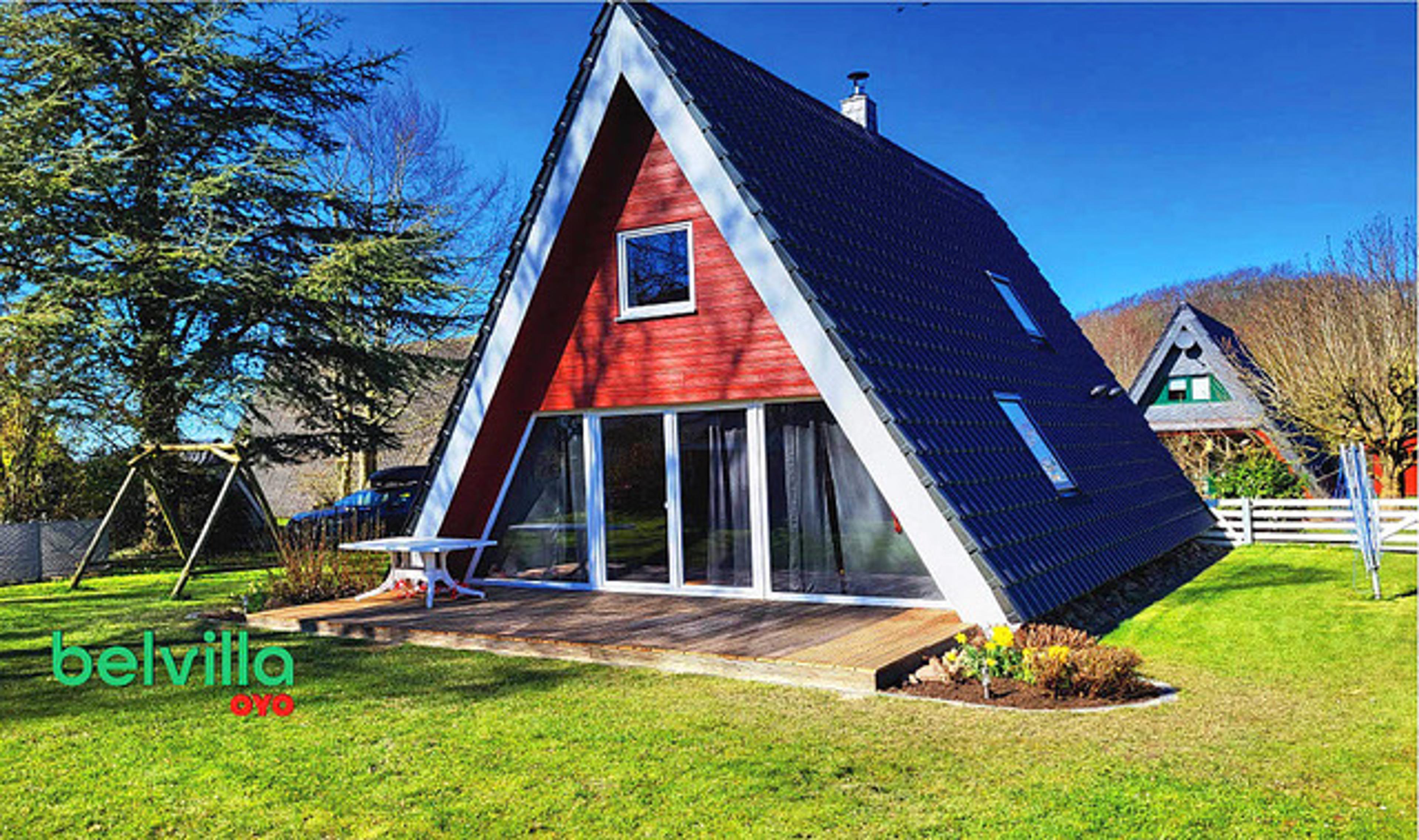 A-Frame-Haus mit roter Fassade, großer Fensterfront und Garten