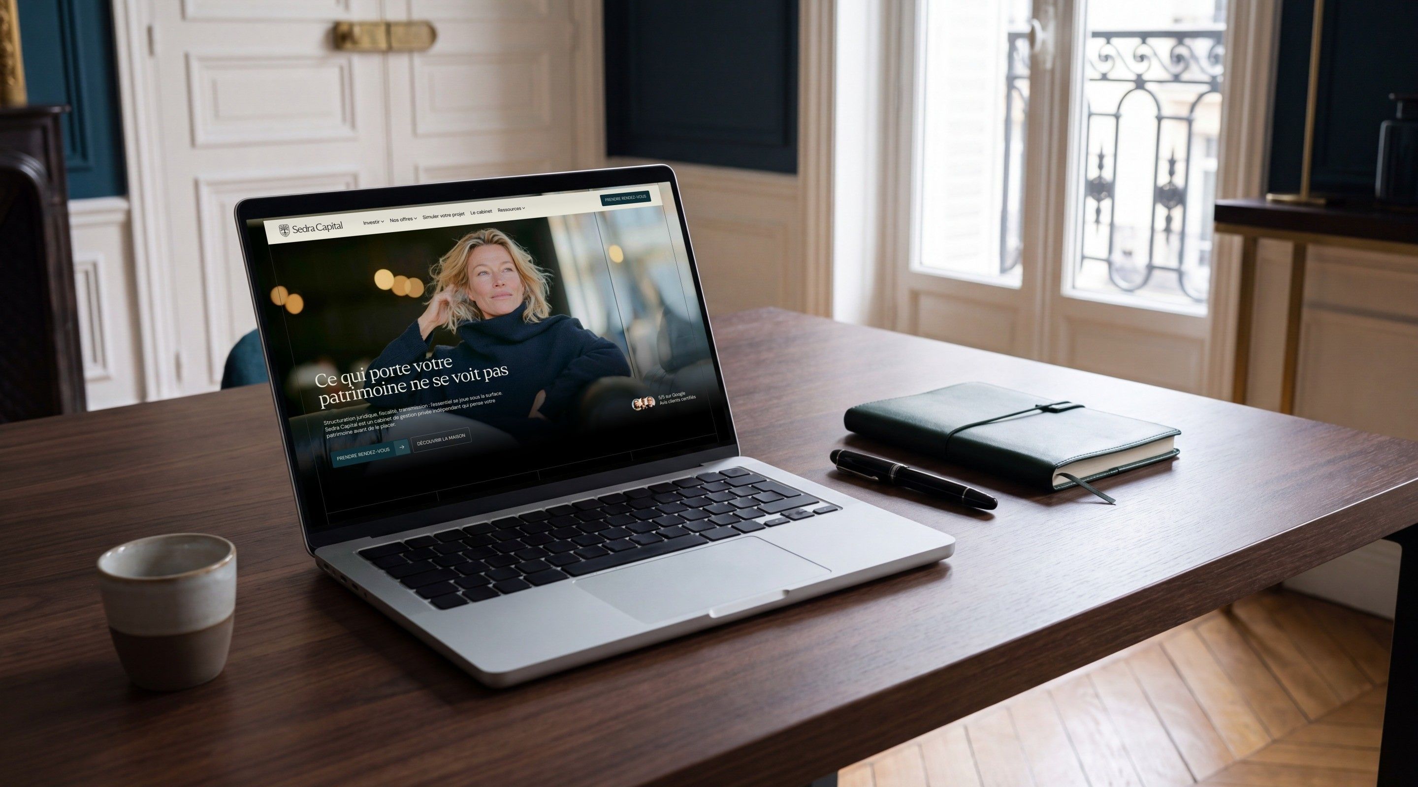 MacBook Pro open on the Sedra Capital home page, “What carries your wealth can't be seen”, in a Haussmann-style office