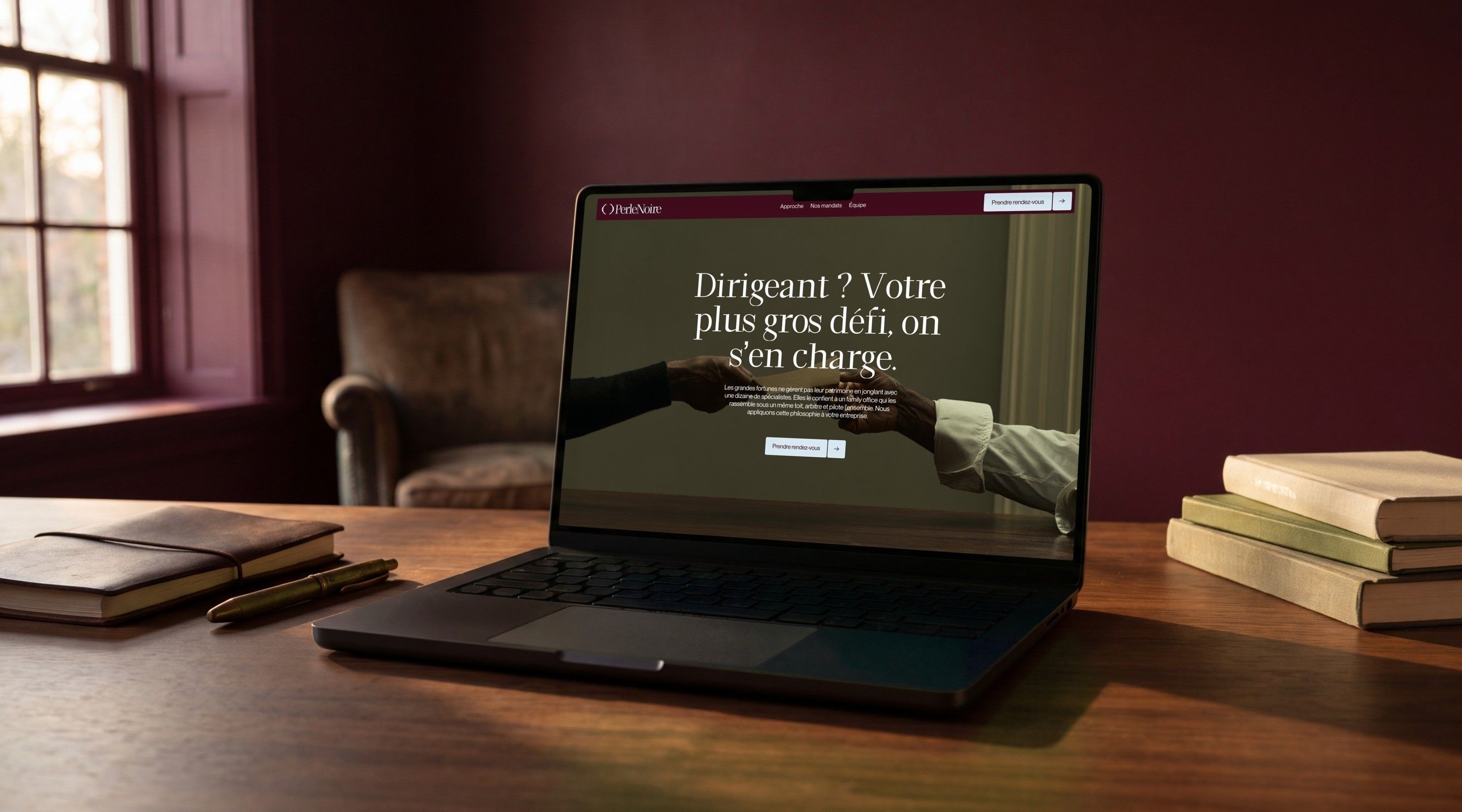 MacBook Pro open on the Perle Noire home page, “Business leader? We'll take on your biggest challenge.”, in an office with burgundy walls
