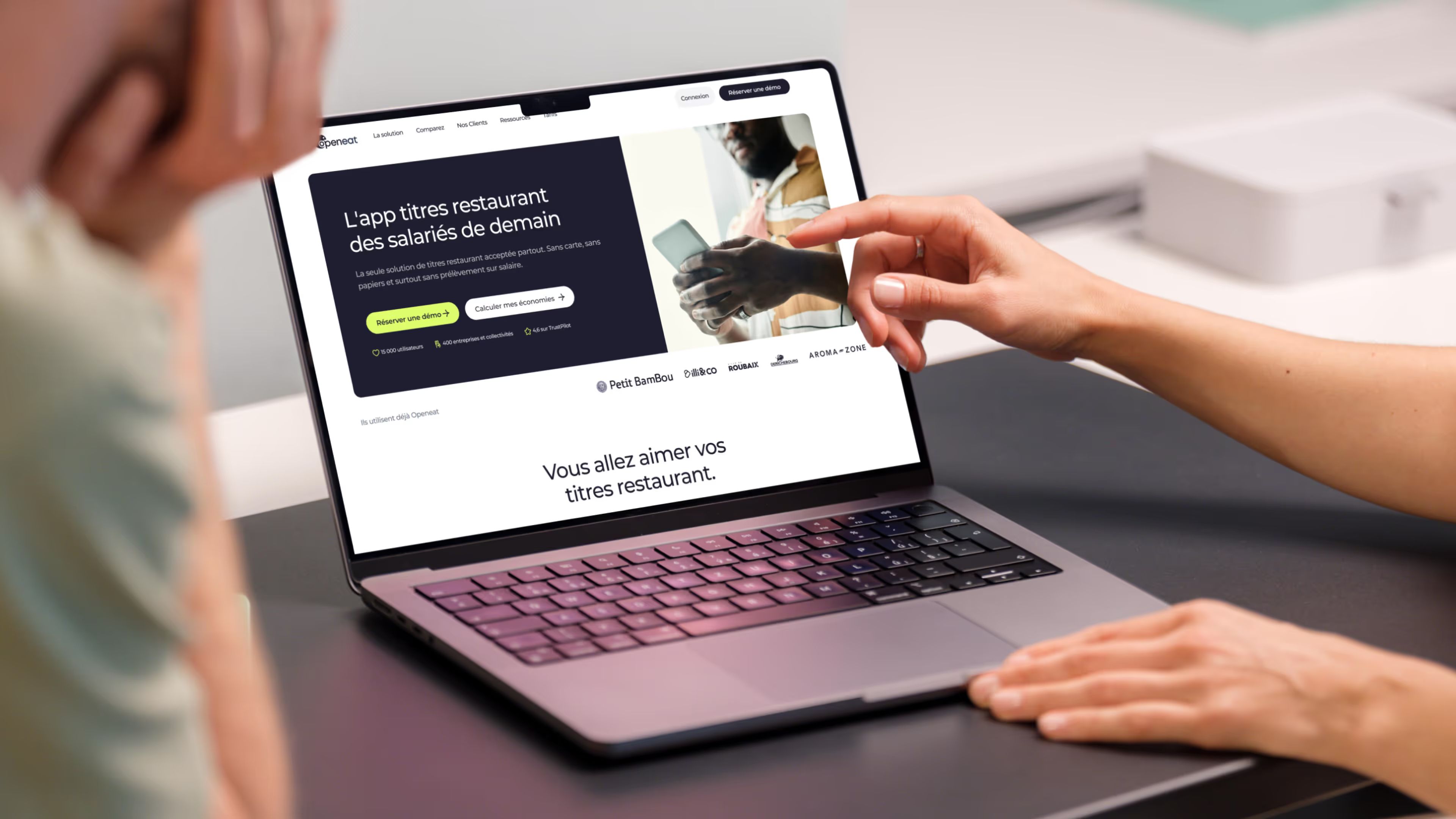 Laptop affichant la page d’accueil Openeat « L’app titres restaurant des salariés de demain », une main pointe l’écran