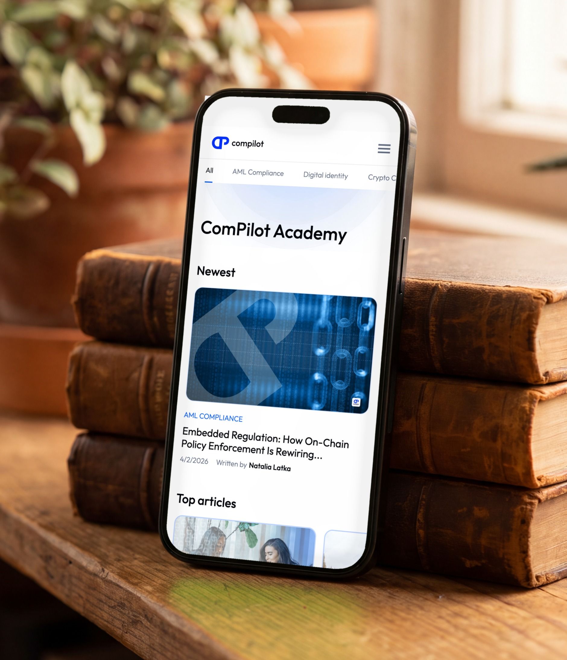 iPhone posé sur des livres, ouvert sur la ComPilot Academy mobile