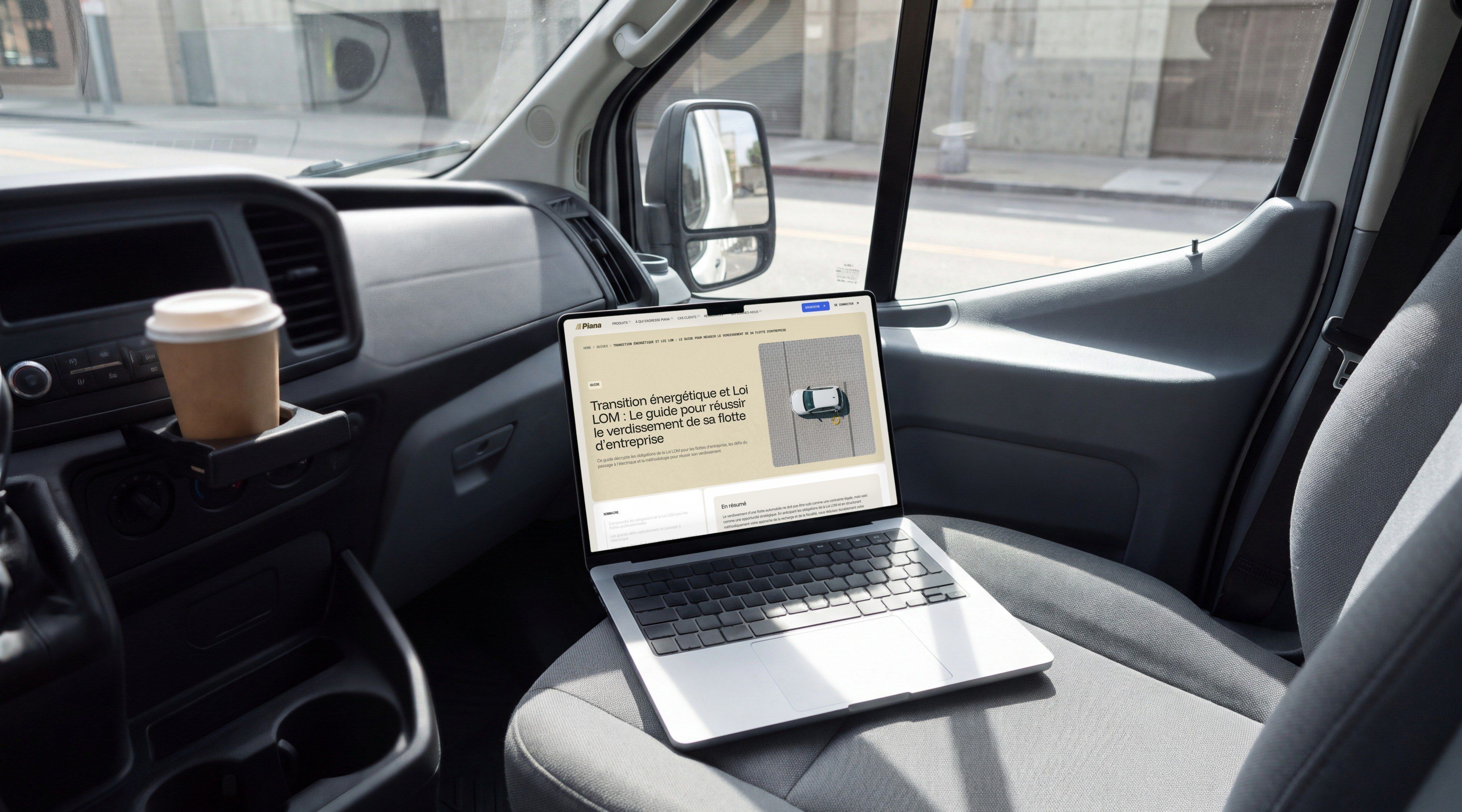 MacBook Pro on the passenger seat of a van, open on Piana's guide to the LOM mobility law