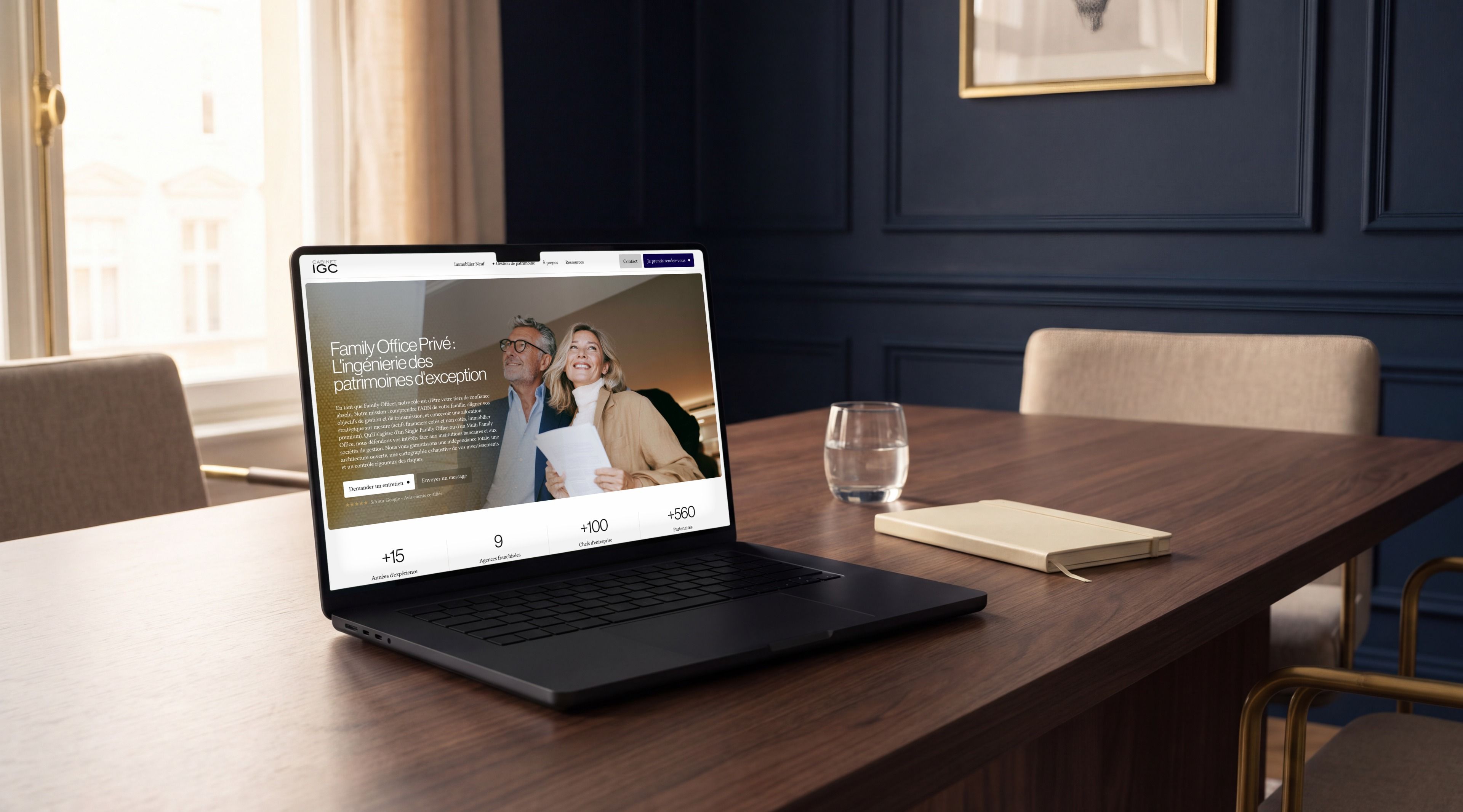 MacBook Pro open on Cabinet IGC's Family Office page, on a meeting table
