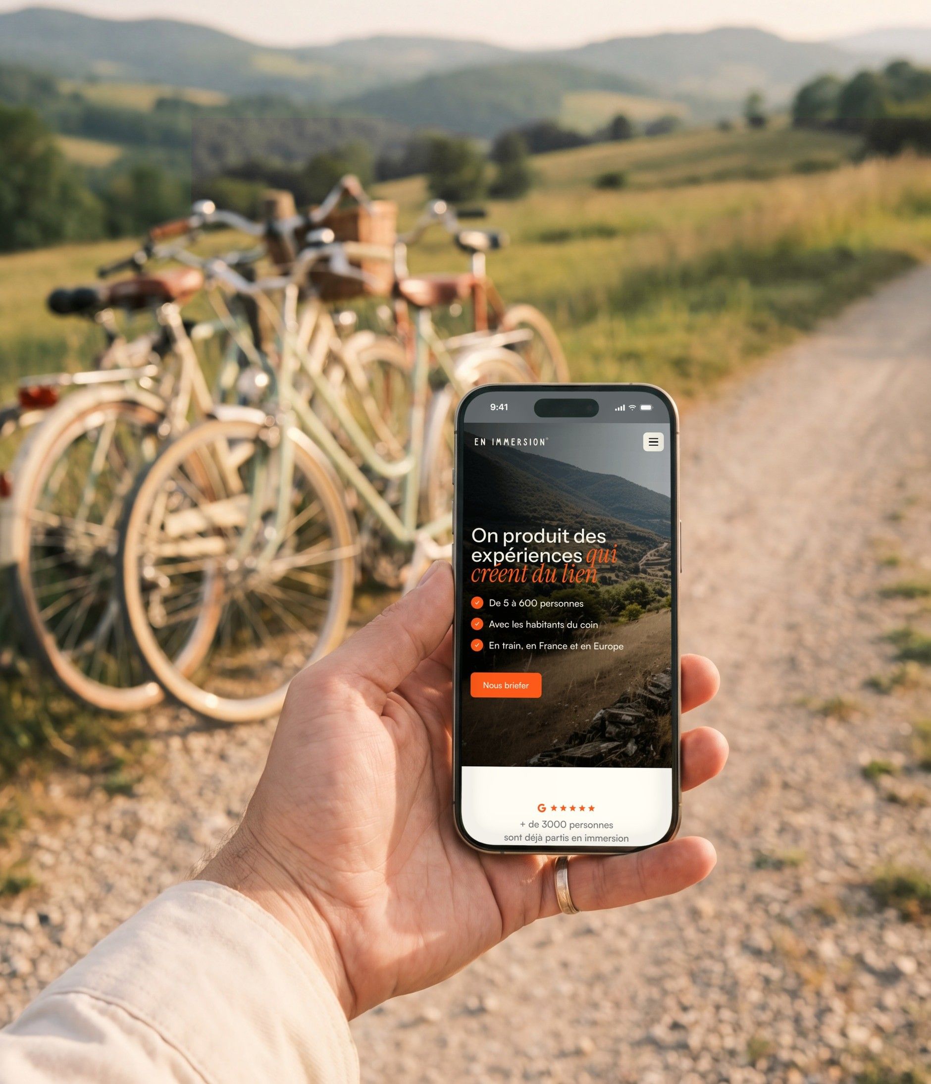 iPhone 16 Pro held on a country path, open on the En Immersion home page