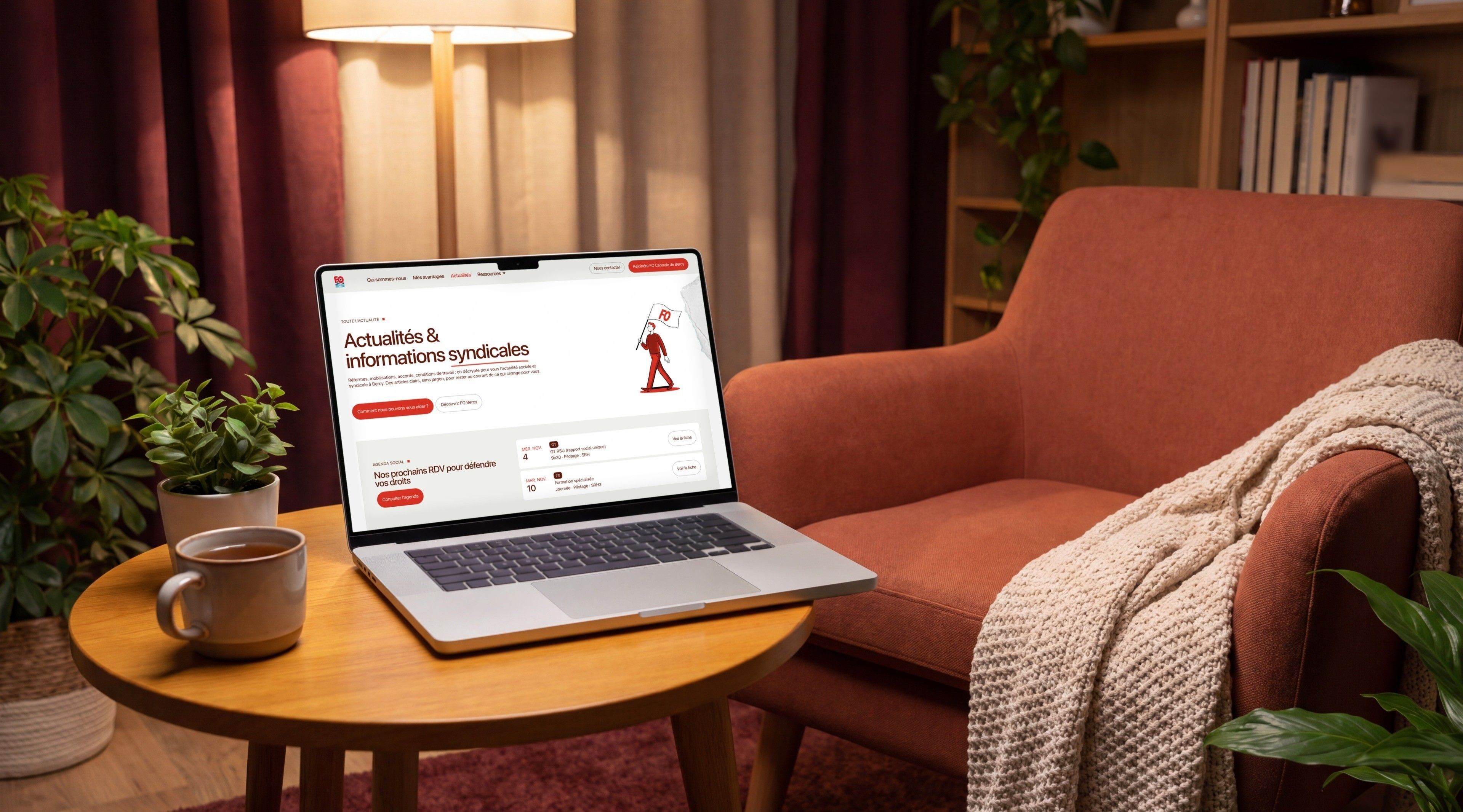 MacBook Pro open on the “News & union information” page, on a coffee table next to an armchair
