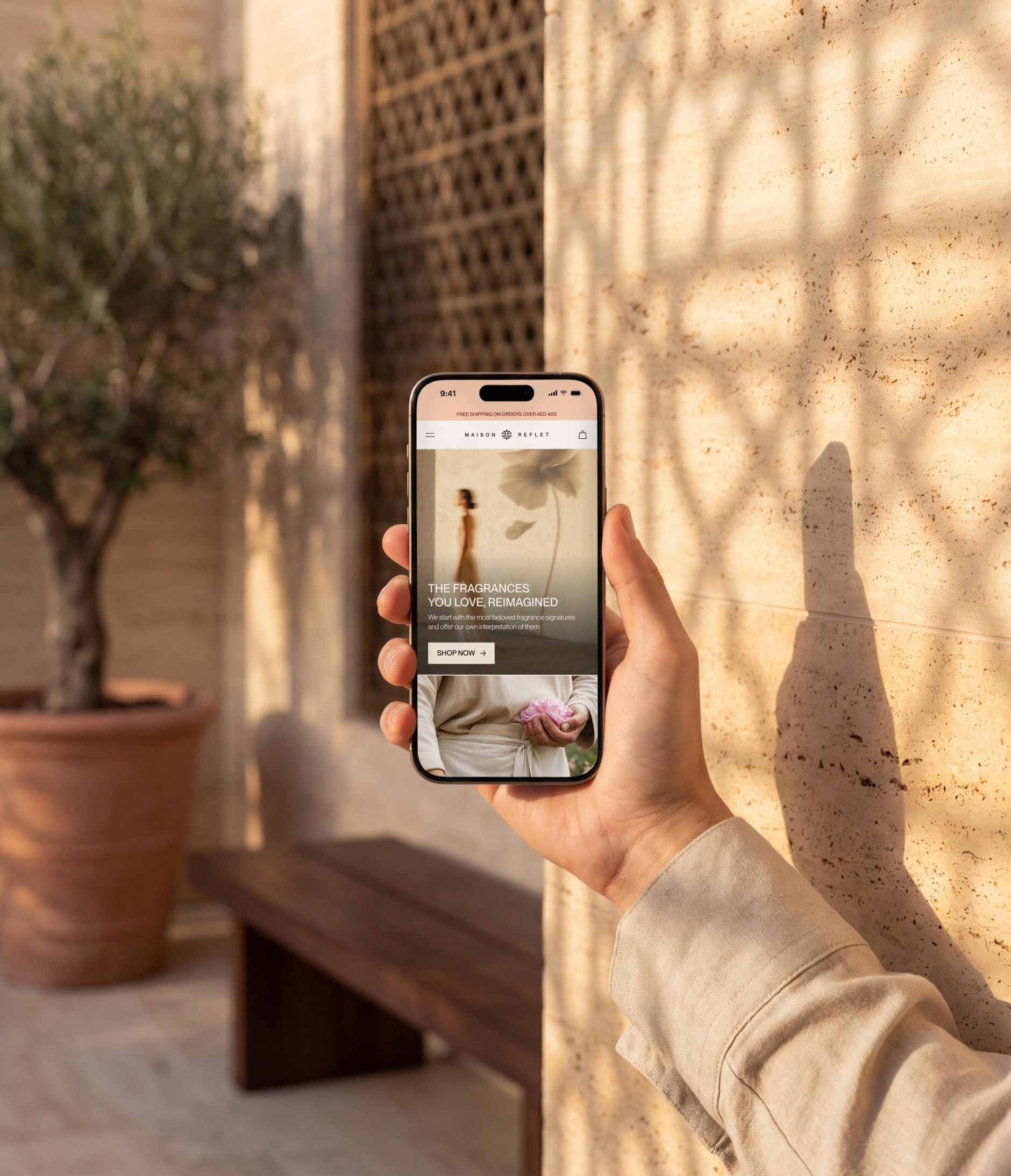 iPhone 16 Pro open on the Maison Reflet mobile home page, in a shaded courtyard