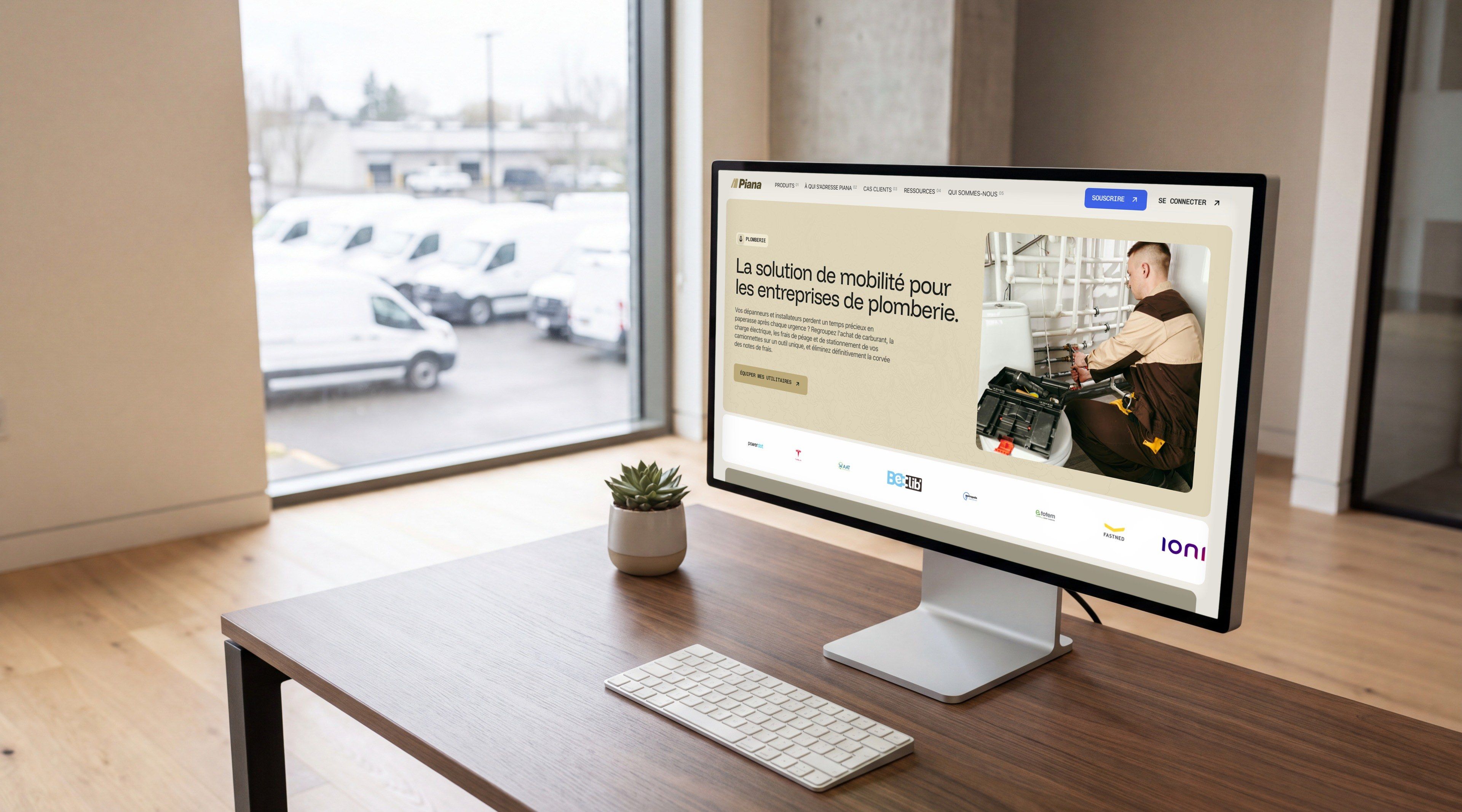 Pro Display XDR on a walnut desk in front of a car park of vans, open on Piana's Plumbing page