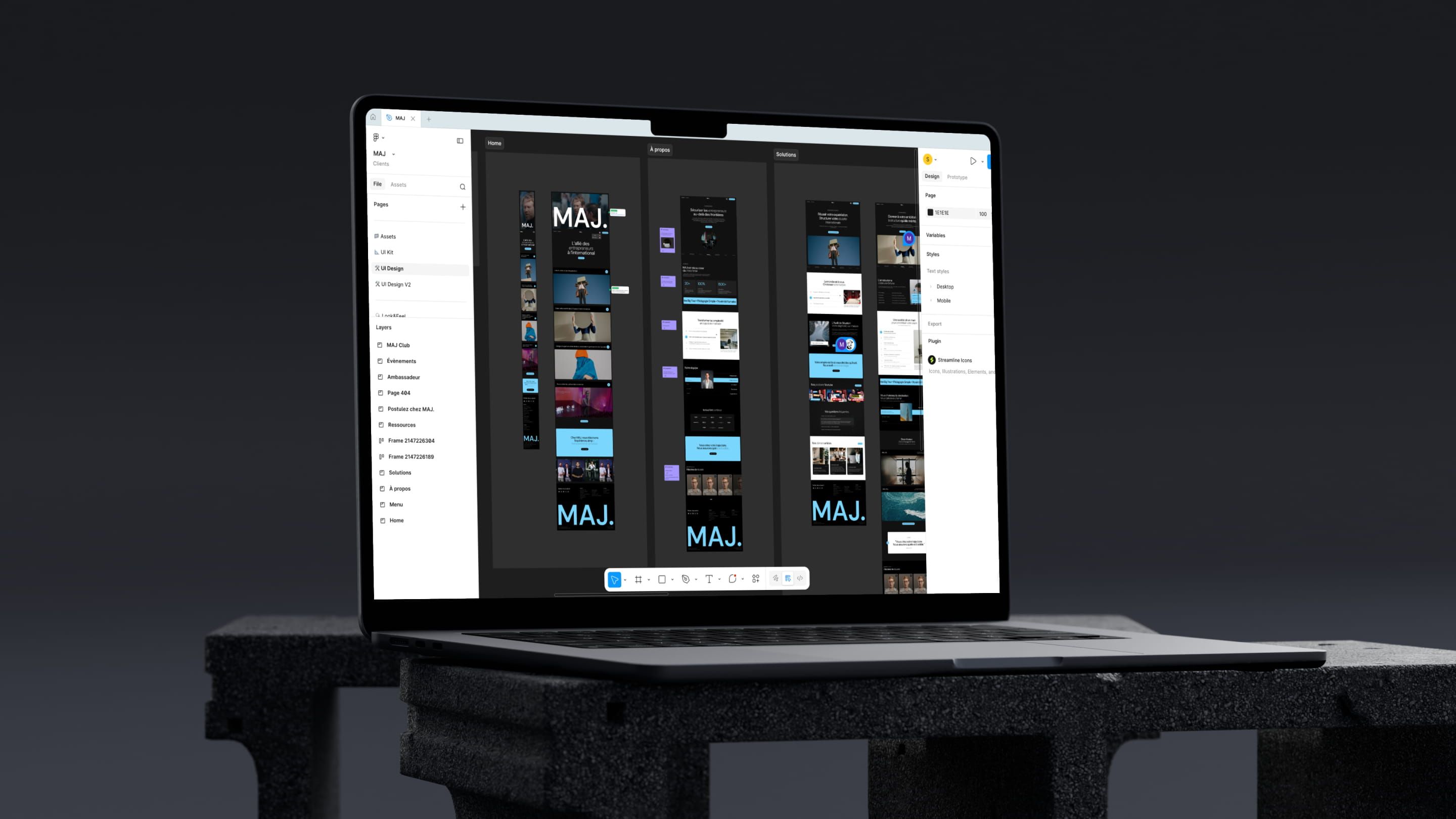 Laptop showing Figma mockups of the MAJ website: Home, About and Solutions pages in black and blue