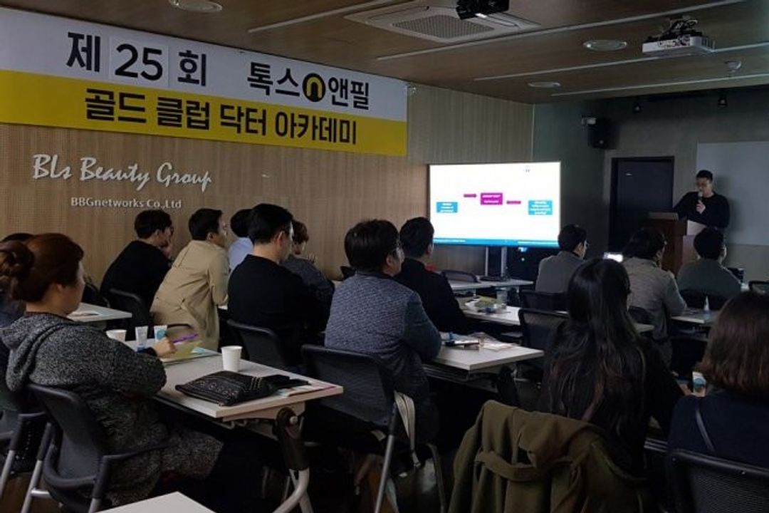 톡스앤필 골드 클럽 닥터 아카데미 현수막이 걸린 강의장에서 참석자들이 책상에 앉아 앞쪽 연단과 화면을 바라보는 모습
