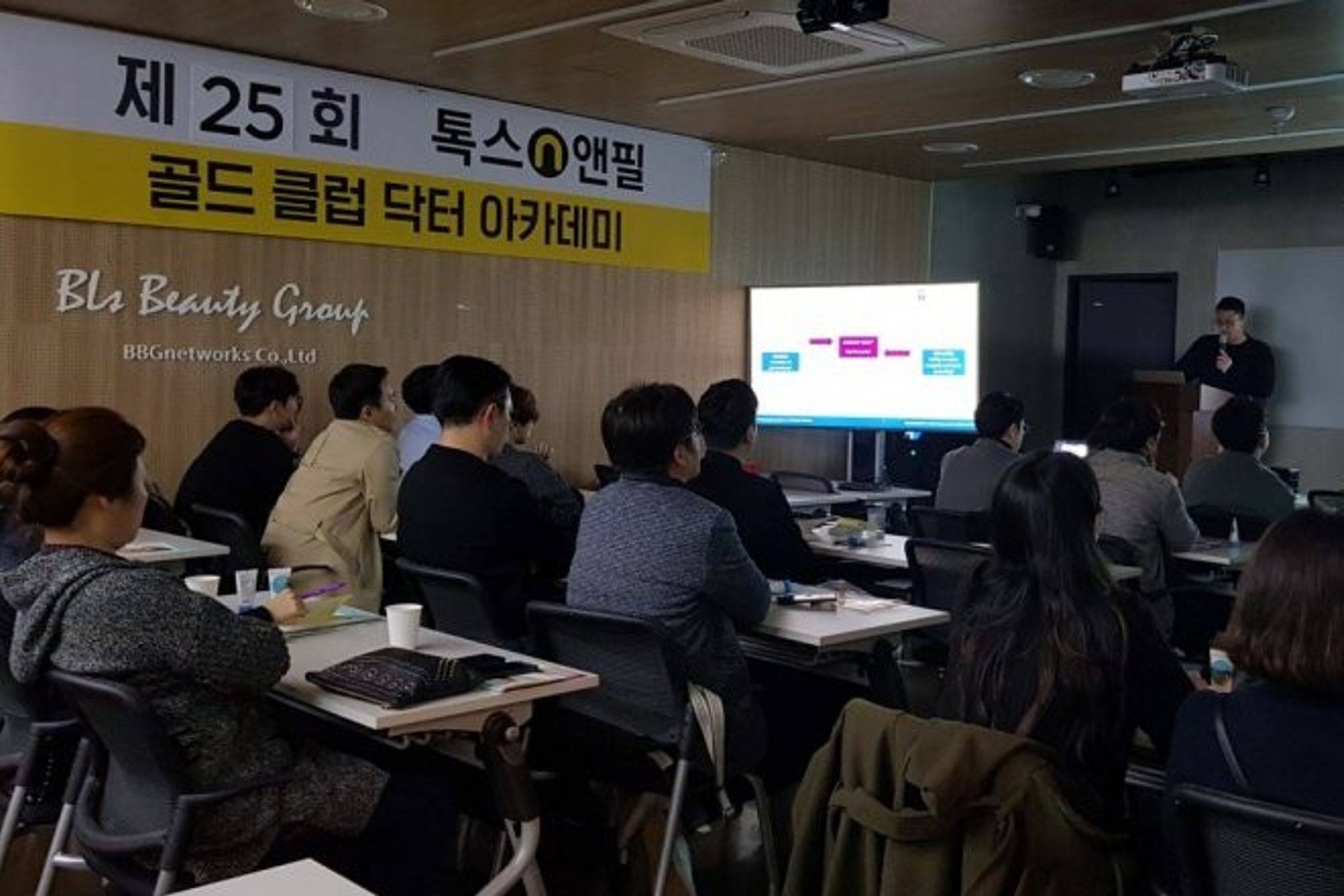 톡스앤필 골드 클럽 닥터 아카데미 현수막이 걸린 강의장에서 참석자들이 책상에 앉아 앞쪽 연단과 화면을 바라보는 모습