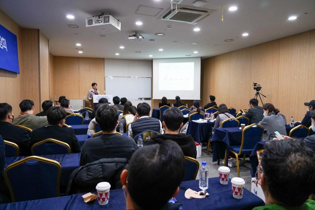 '2022 메디게이트 성공개원&학술 박람회' 연단에서 연자가 발표하고 참석자들이 화면을 보고 있는 강연장