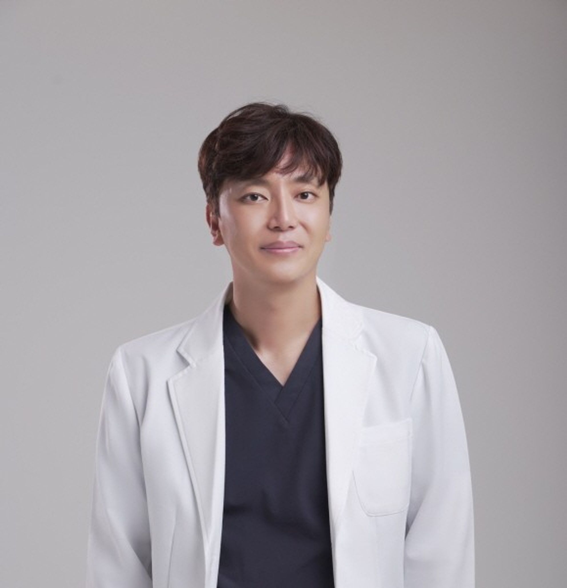 회색 배경 앞에서 흰 가운을 입은 한 사람의 상반신 프로필 사진
