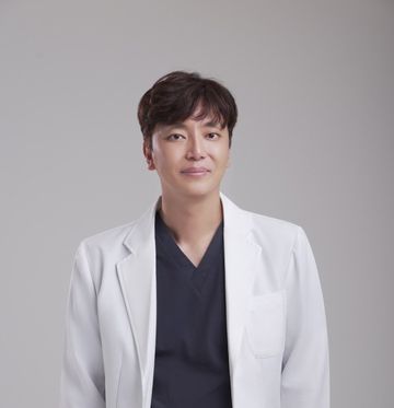 회색 배경 앞에서 흰 가운을 입은 한 사람의 상반신 프로필 사진