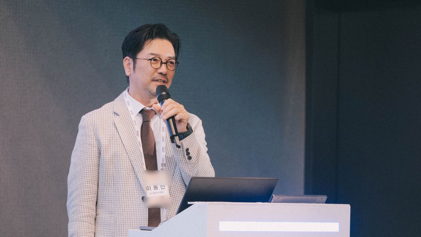 '이동진' 명찰을 단 이동진 원장이 연단 옆에 서서 마이크를 들고 말하고 있다