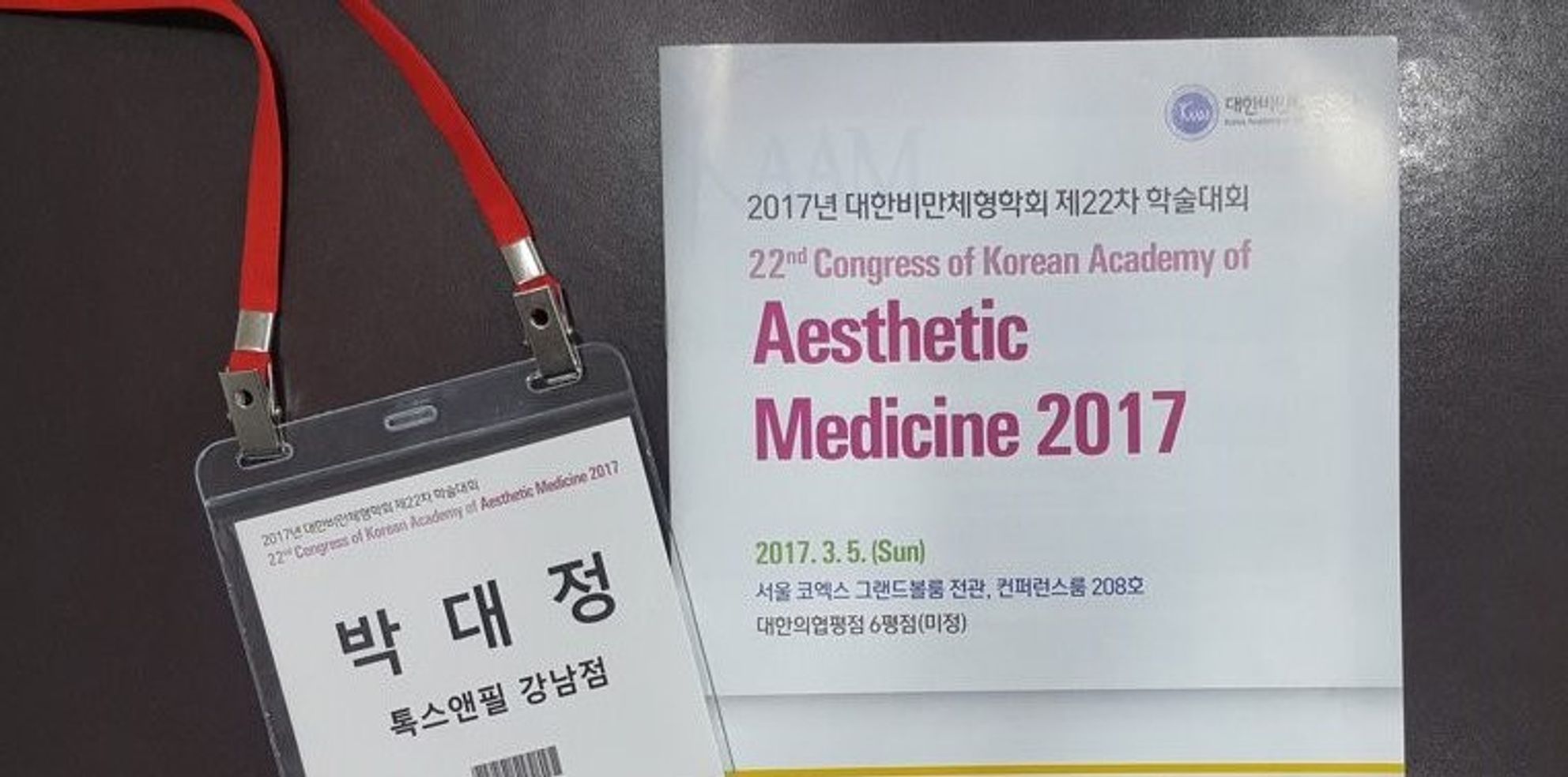 학술대회 명찰과 '22nd Congress of Korean Academy of Aesthetic Medicine 2017' 책자 표지가 나란히 놓인 모습