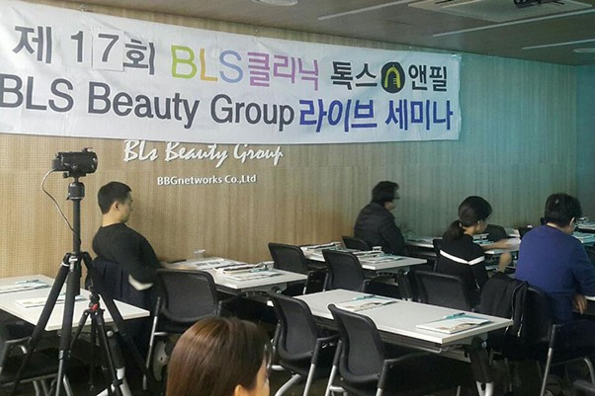 BLS클리닉과 톡스앤필 이름이 함께 적힌 라이브 세미나 현수막 아래 강의장에서 참석자들이 책상에 앉아 있는 모습