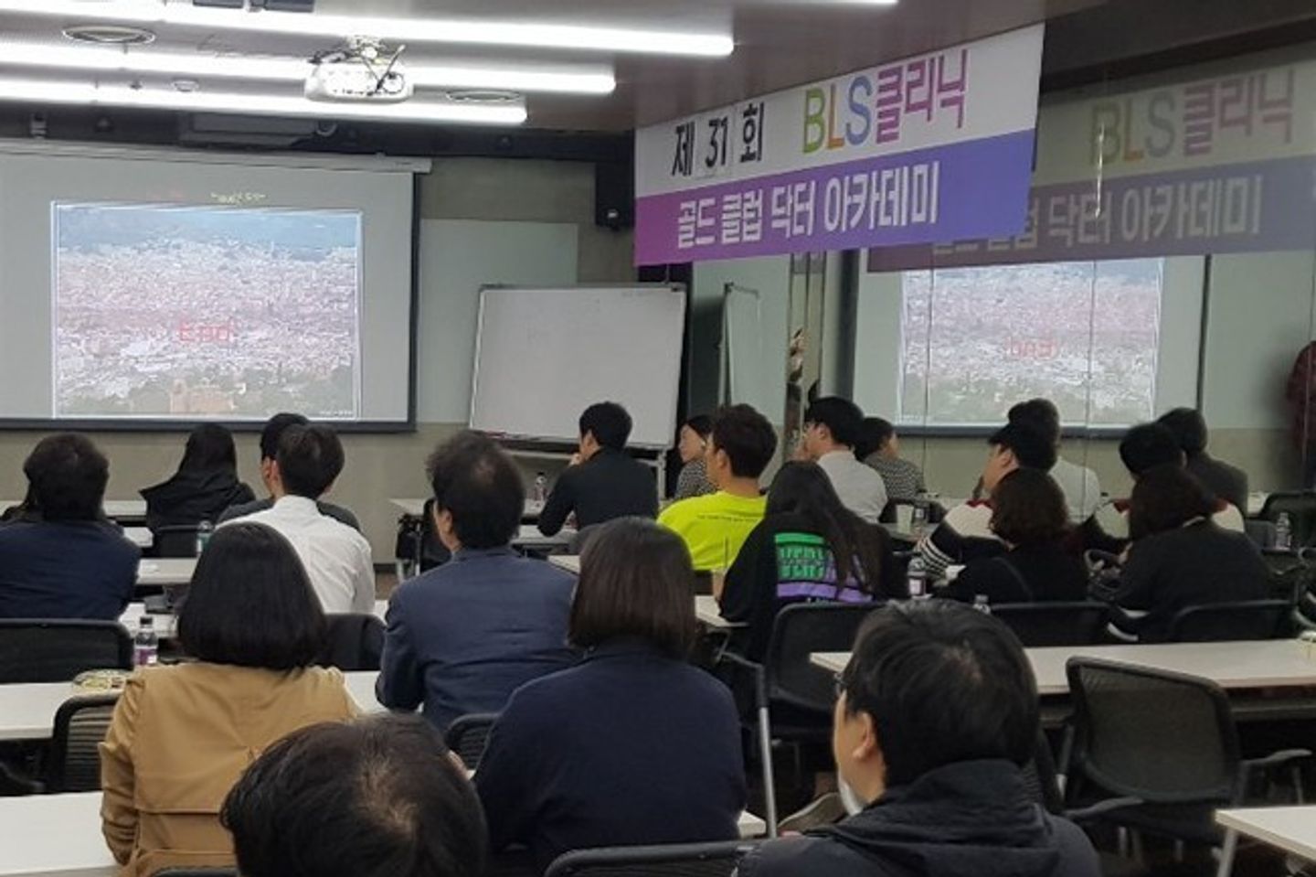 현수막이 걸린 강의실에서 참석자들이 앉아 앞쪽 화면을 바라보는 장면