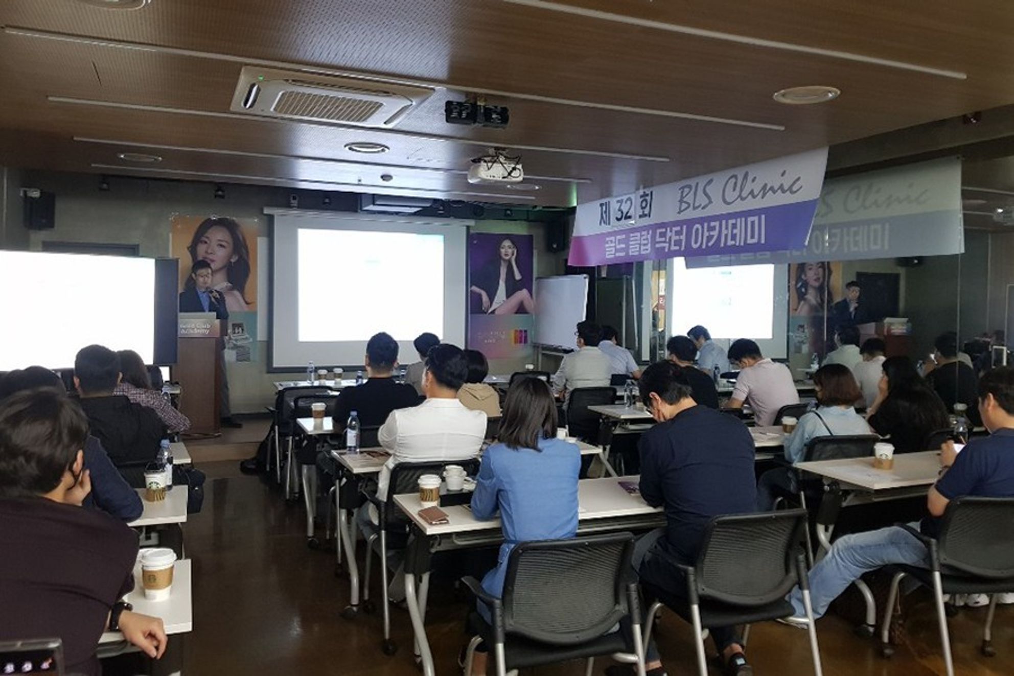 현수막이 걸린 강의실에서 참석자들이 앉아 앞쪽 연단을 향한 장면