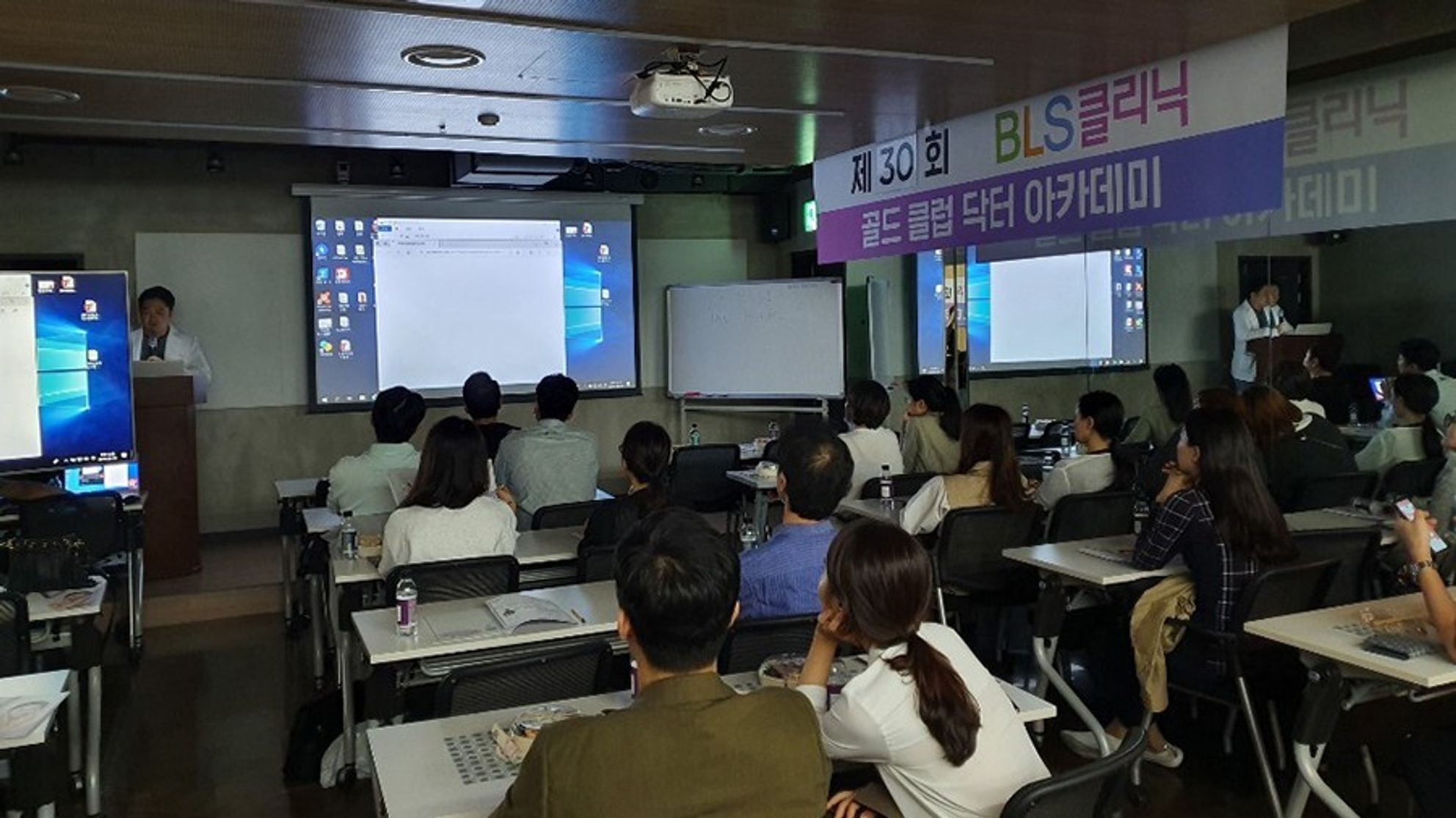 현수막이 걸린 강의실에서 참석자들이 앉아 연단 쪽을 향한 장면