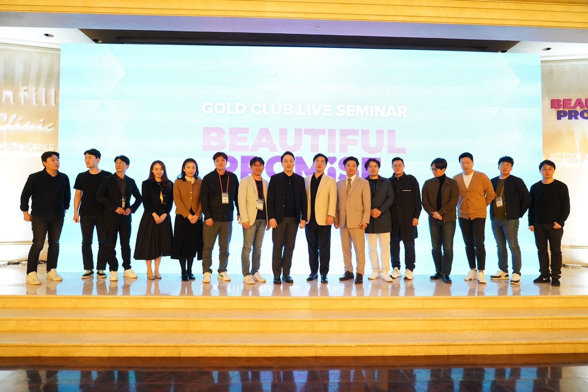 'GOLD CLUB LIVE SEMINAR BEAUTIFUL PROMISE'가 띄워진 무대 화면 앞에 참석자들이 한 줄로 서서 단체 사진을 찍고 있다