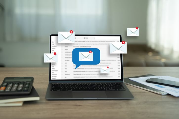 A photo of email icons in front of a computer screen