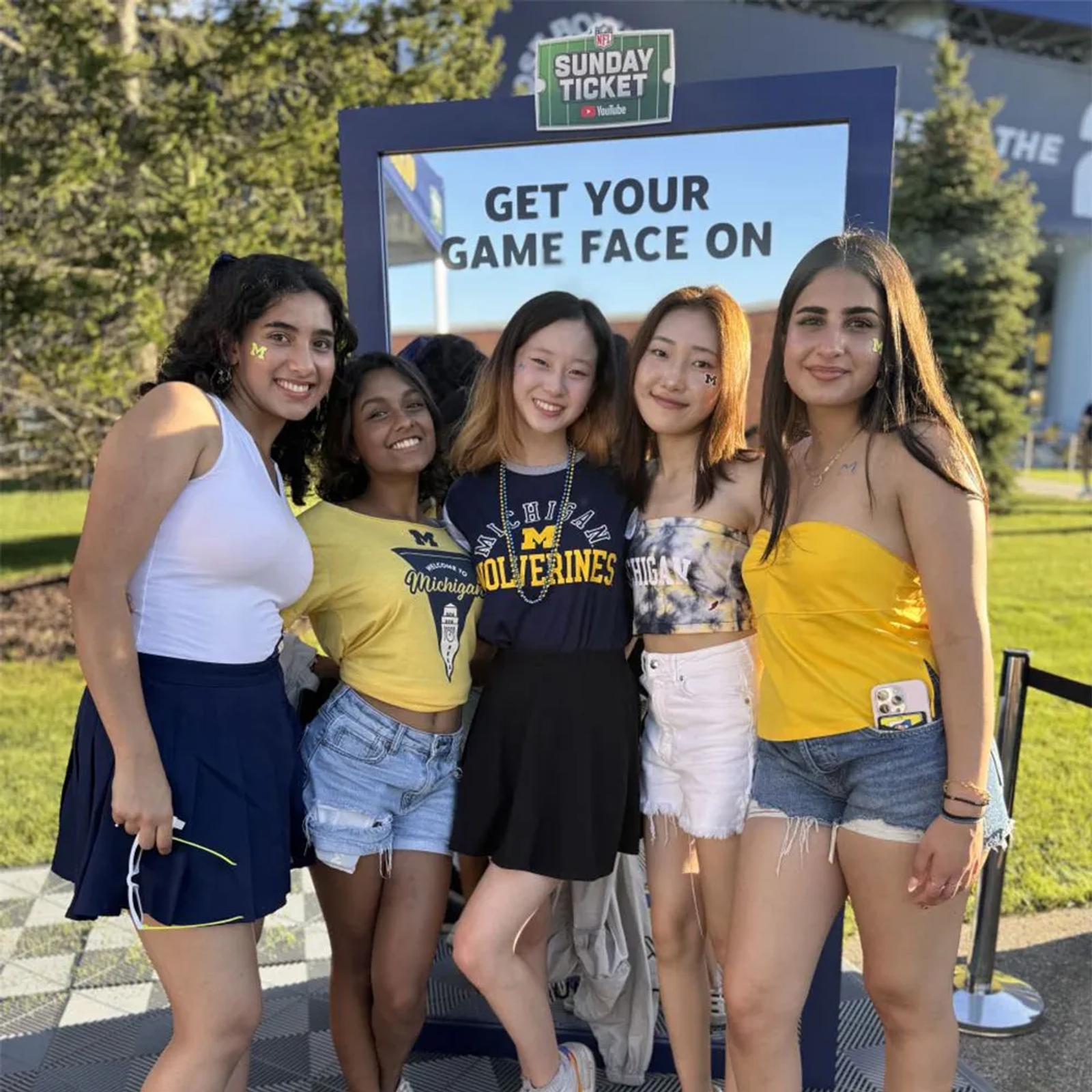 Image of Michigan students posing at a Get Your Game Face On mirror at the YouTube NFL Sunday Ticket activation
