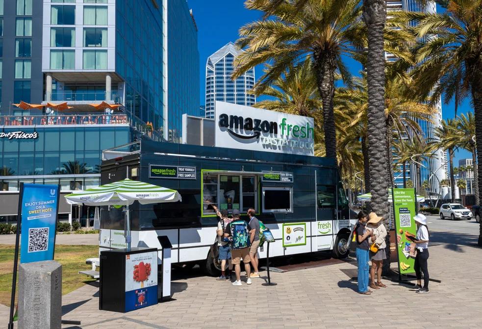 image of the Amazon Fresh Taste Truck parked in an urban plaza offering free samples
