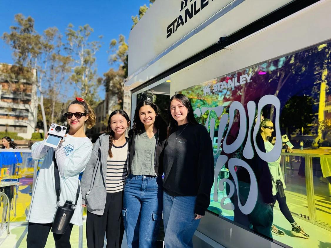 Image of four young women posing in front of a Stanley branded experiential marketing truck at an outdoor campus event