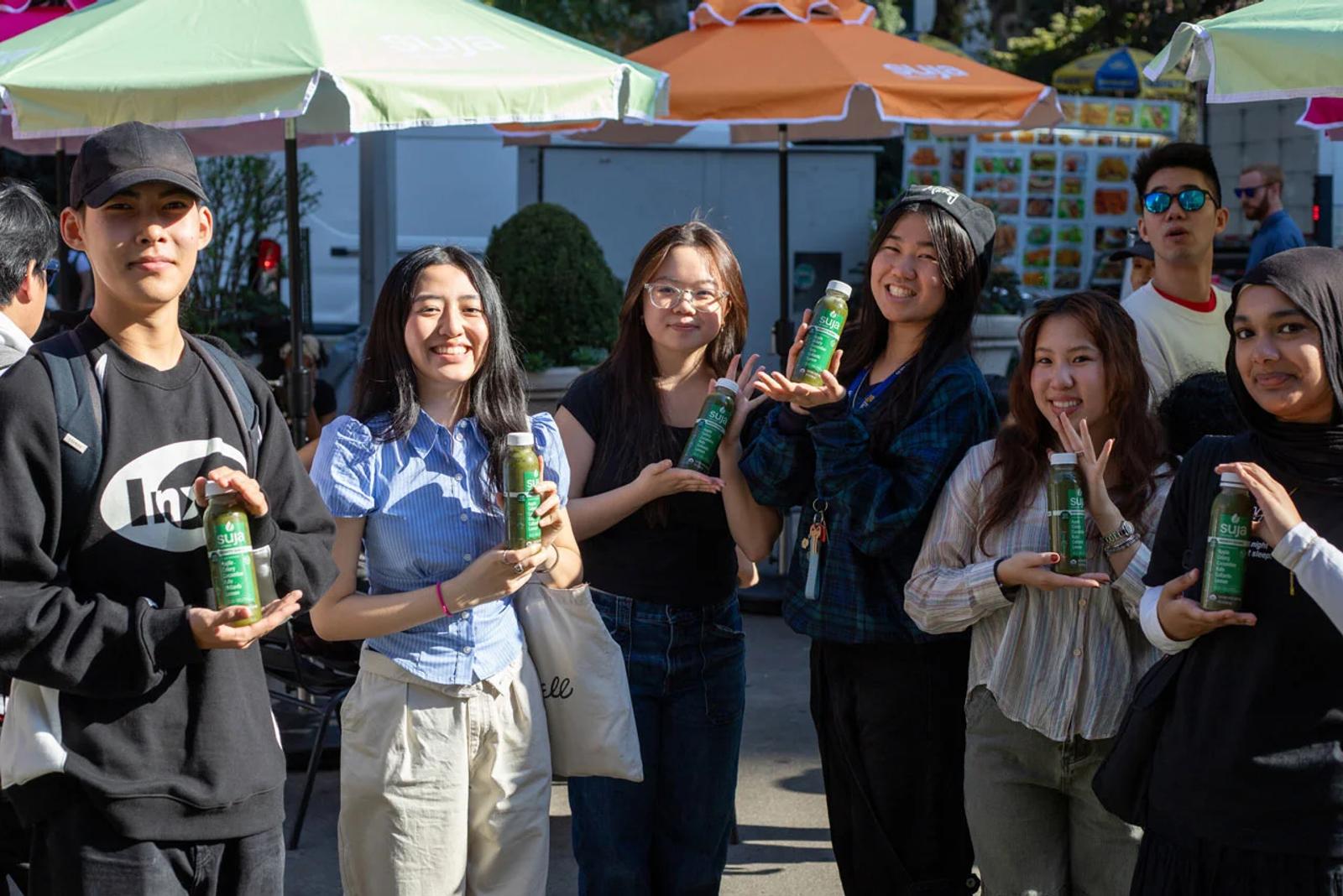 image of a group of smiling people holding Suja Organic green juice bottles outdoors