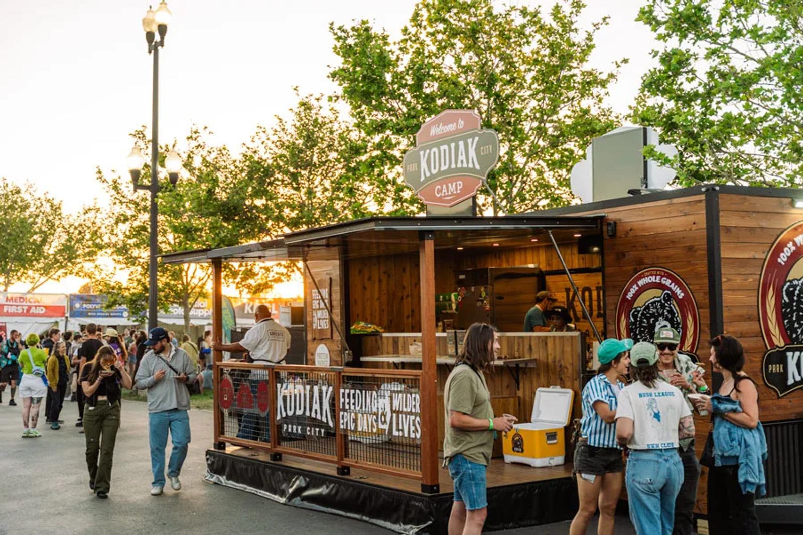 Visitors gather around a rustic Kodiak Cakes camp-style food truck at a busy outdoor event