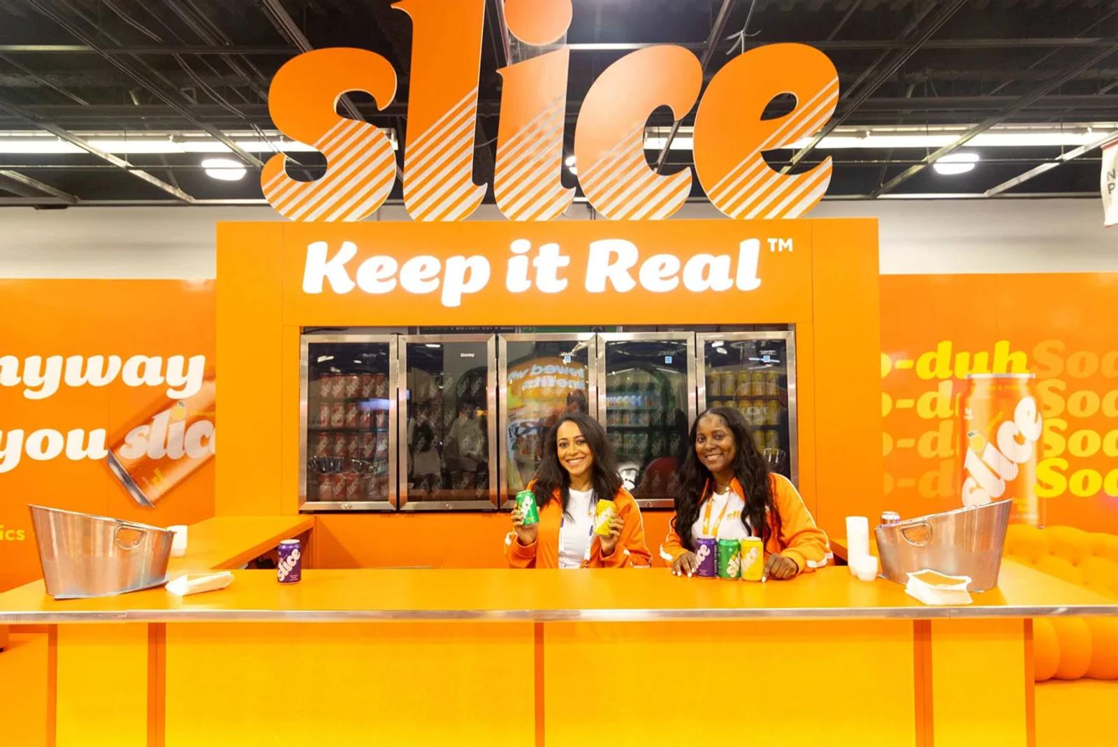 Image of two brand ambassadors at the Slice soda trade show booth.webp